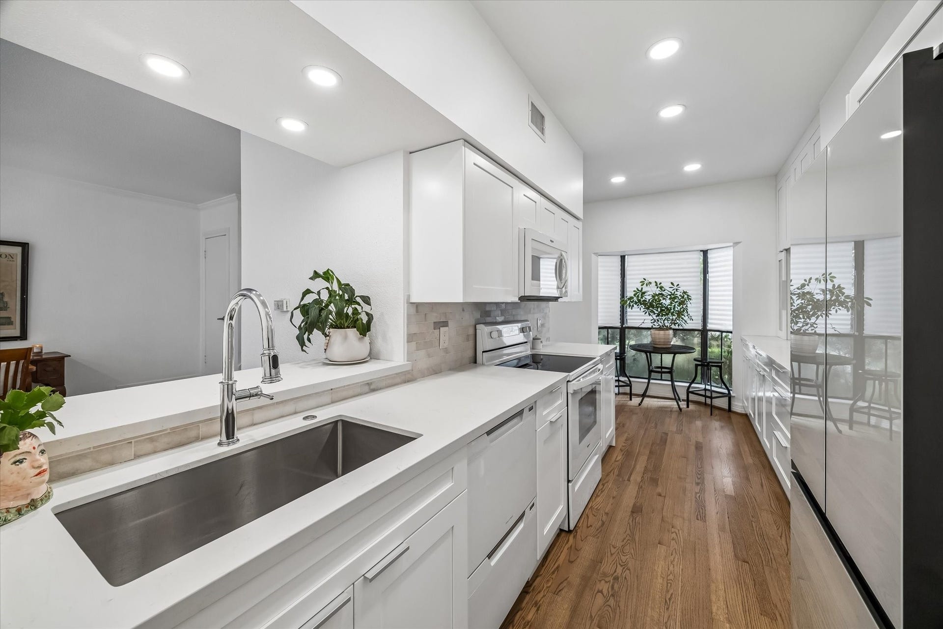 Bright and modern kitchen with sleek white cabinetry, updated appliances, updated sink, faucet, and disposal. New pantry.