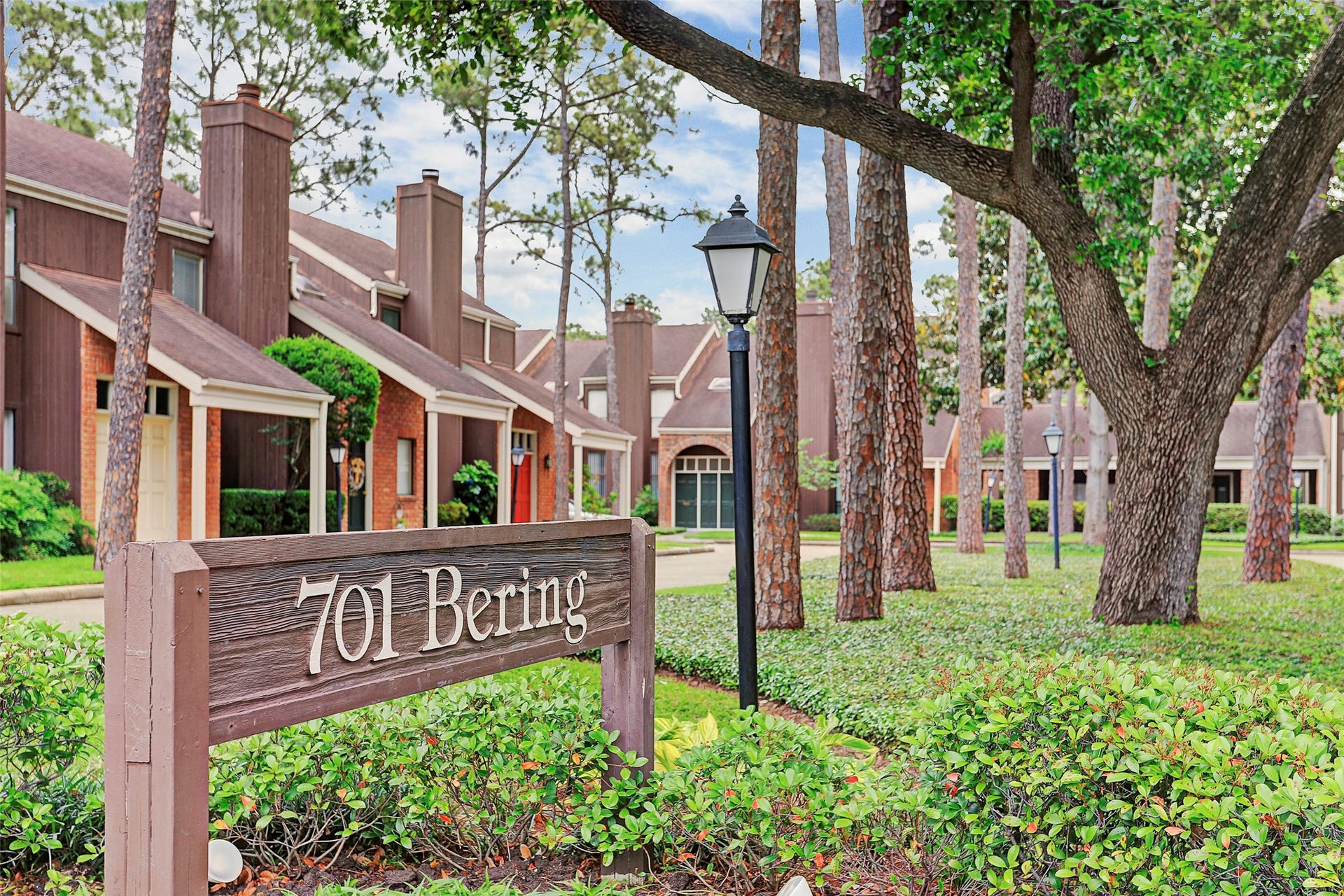 Charming townhomes nestled among tall trees and lush greenery, featuring classic architecture with warm, inviting exteriors.