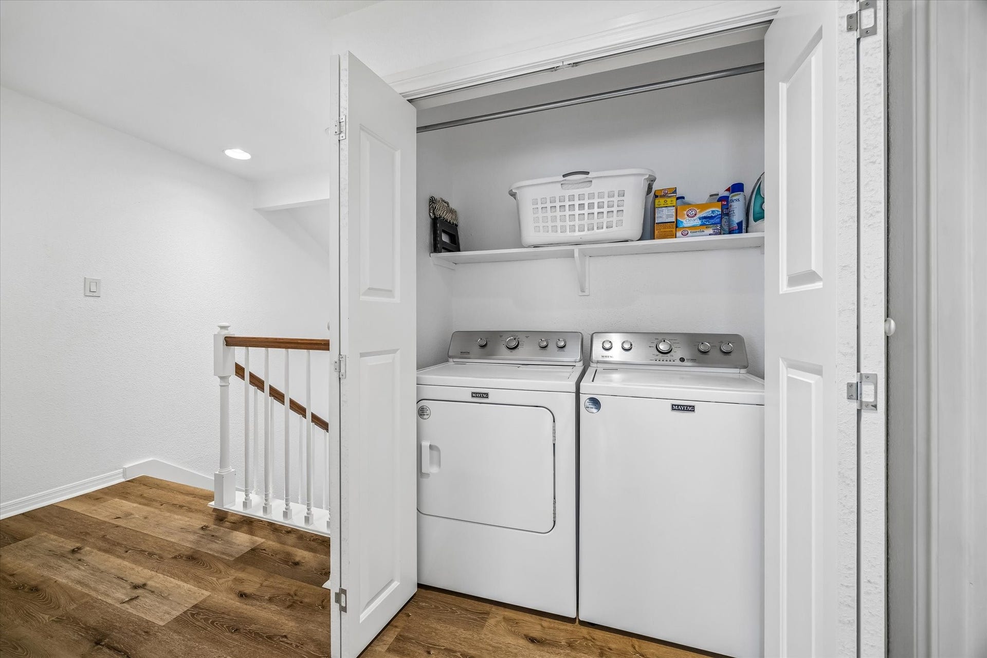 Convenient laundry nook with a Maytag washer and dryer (2022) neatly tucked behind bi-fold doors, featuring a shelf for storage.