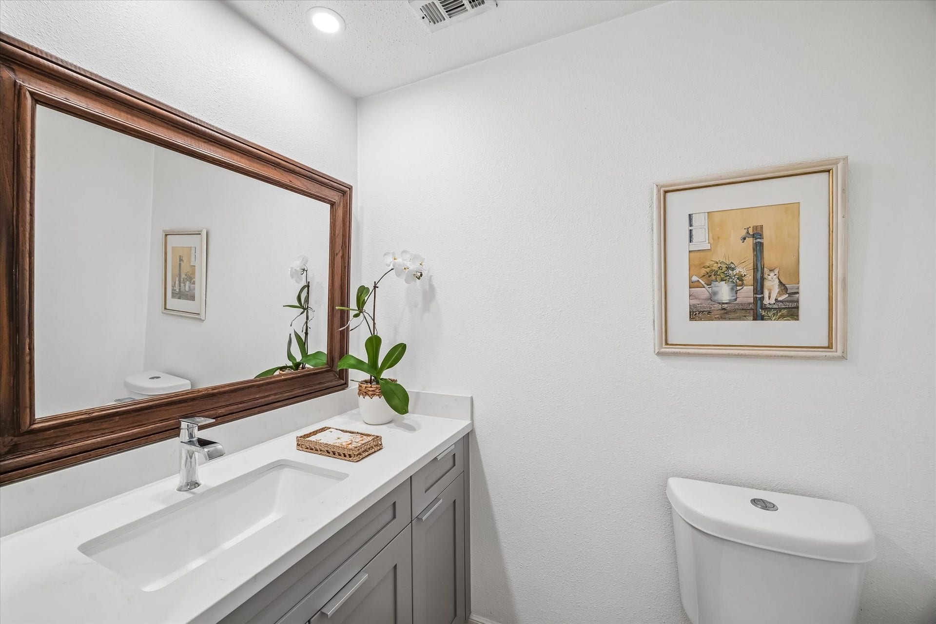 Downstairs half bathroom, fully renovated with quartz countertop, new toilet refinished floors, features an antique oversize mirror.