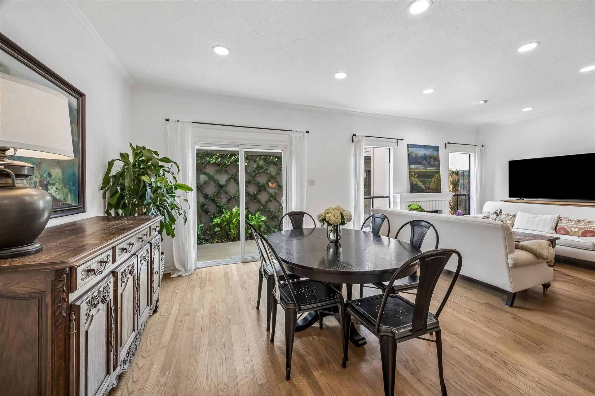 Bright and inviting open-plan living area with hardwood floors, featuring new sliding glass doors. New crown, molding, and baseboards throughout.
