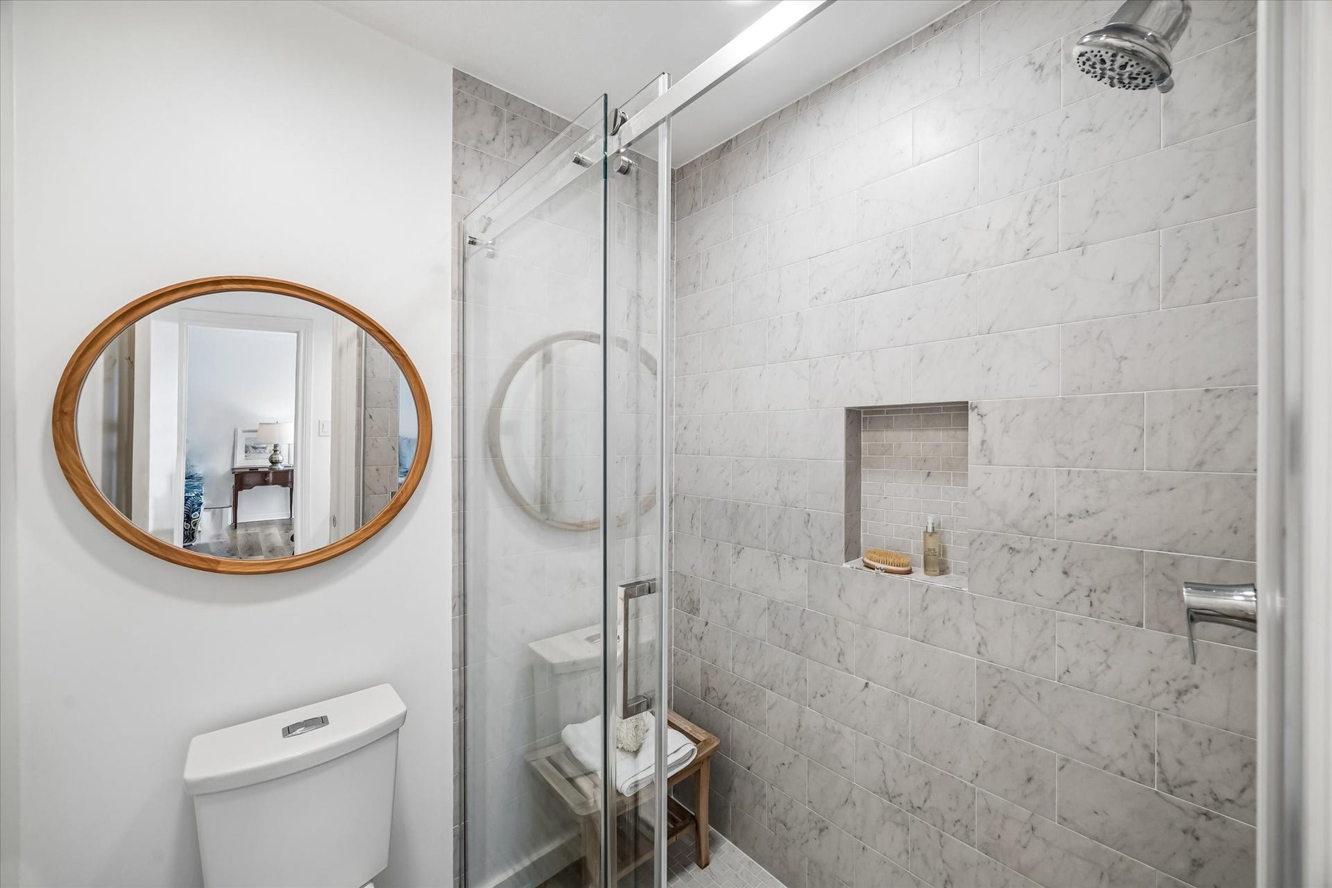 Elegant bathroom featuring a spacious marble-tiled shower with a glass door and built-in niche.