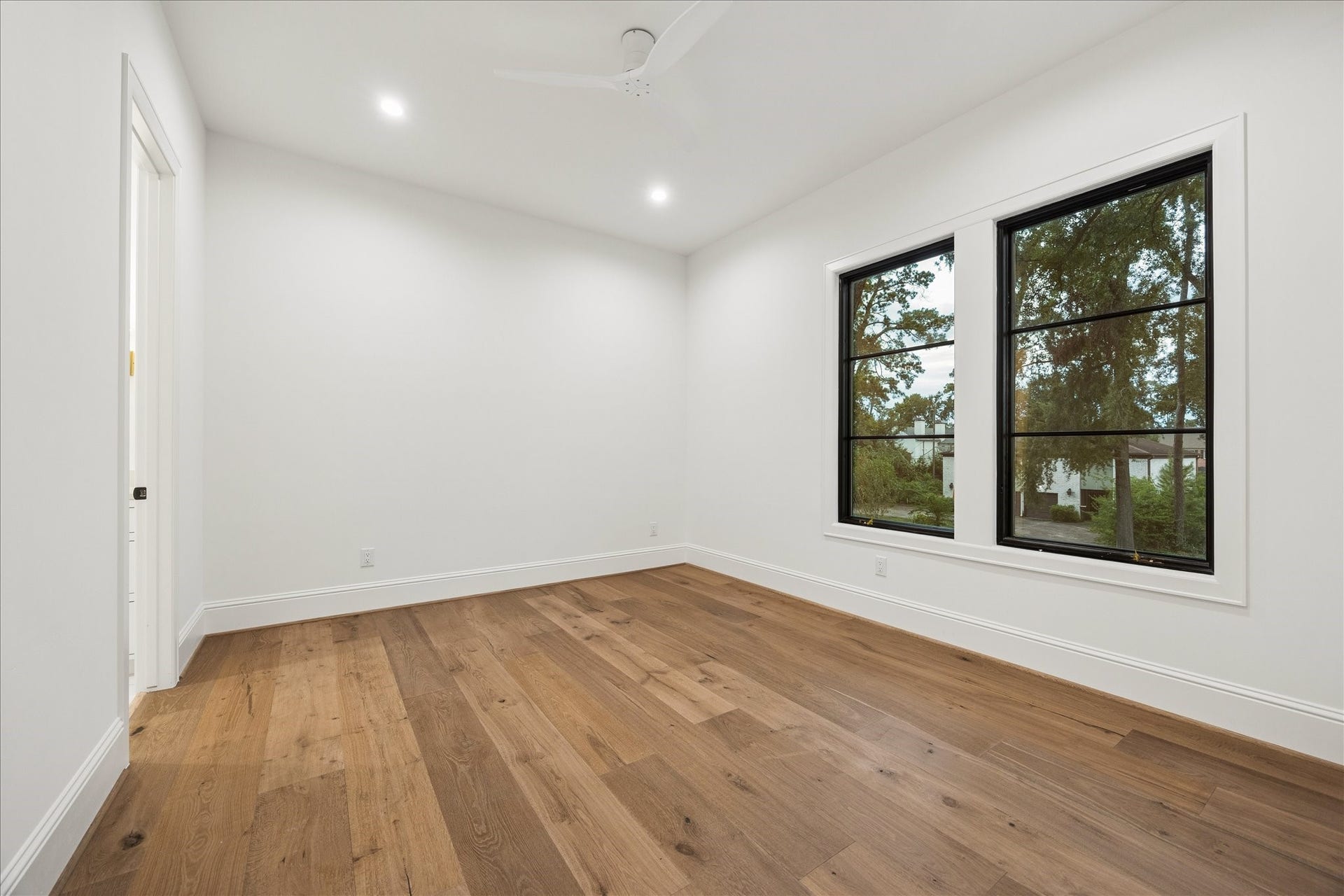 7719 Bryonwood Drive, Houston, TX 77055 Large black-framed windows bring tree views into this bedroom.