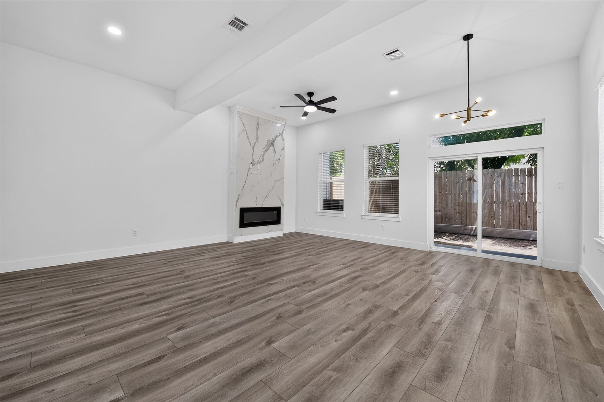 2911 Wichita Street, Houston, TX 77004 Light-filled and thoughtfully designed, this spacious living room features refined transom detailing, generous windows, and sliding glass doors that beautifully connect indoor and outdoor living.