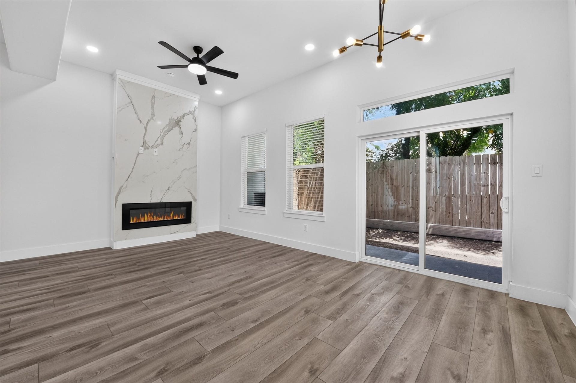 2911 Wichita Street, Houston, TX 77004 Designed for effortless indoor-outdoor living, this spacious living area features a warm fireplace, expansive sliding doors, a covered porch, and a tranquil backyard retreat.