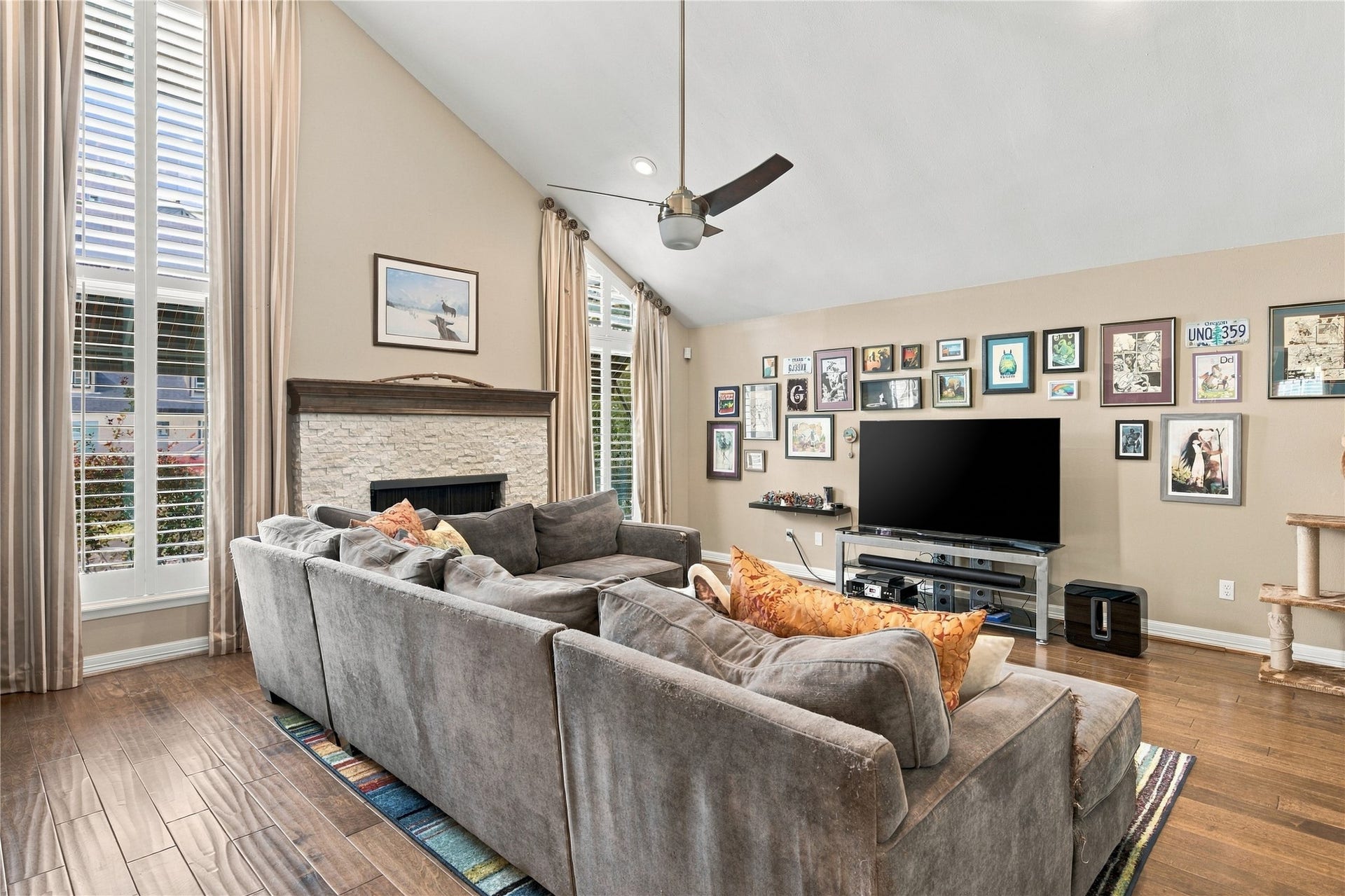 3211 Chris Drive, Houston, TX 77063 This spacious living room features a stacked-stone gas-log fireplace with dark wood mantel, a dramatic vaulted ceiling & floor-to-ceiling plantation-shuttered windows that fill the space with natural light.