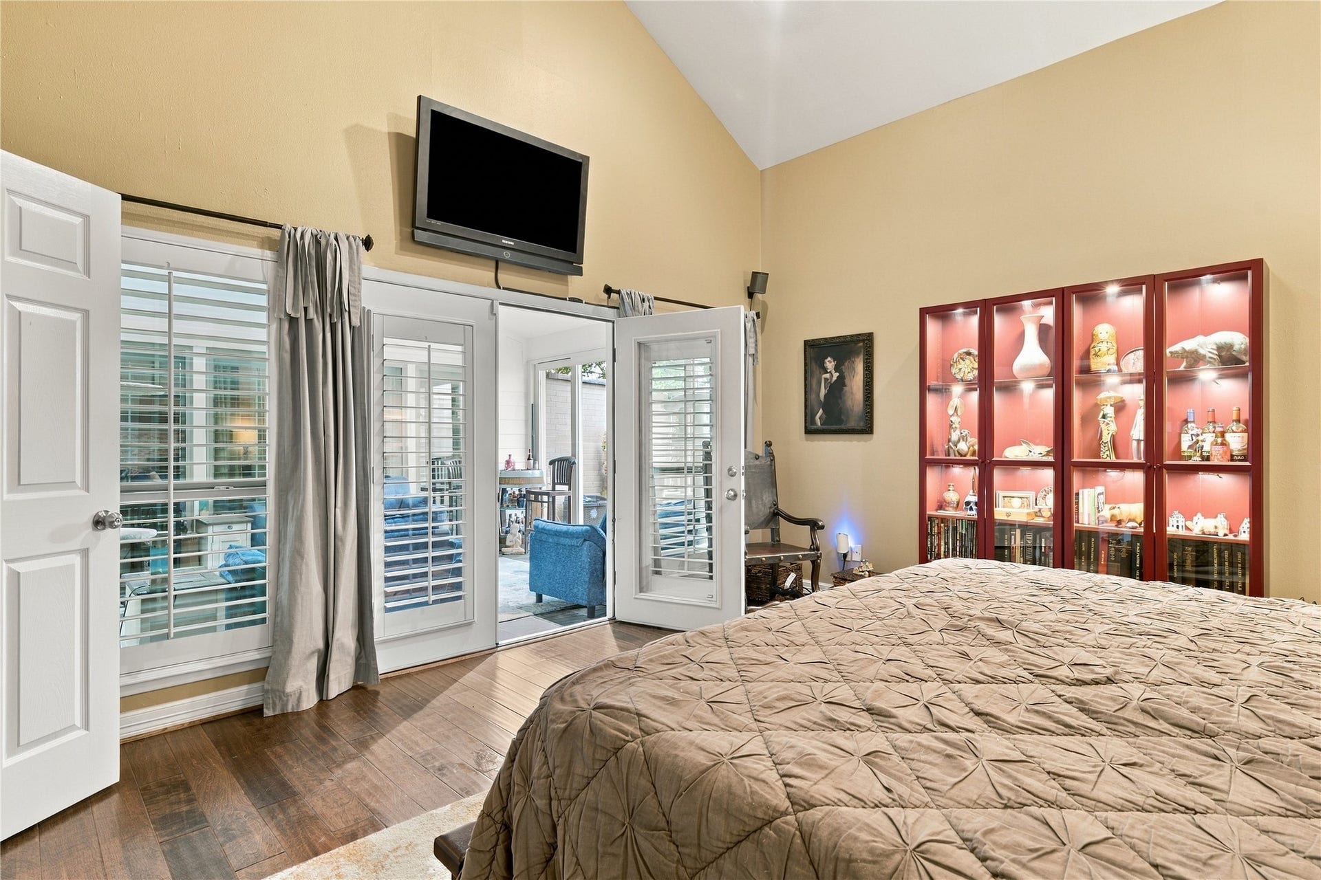 3211 Chris Drive, Houston, TX 77063 Shuttered French doors & matching windows line one wall of the primary, with a view through the sunroom to the patio beyond. Natural light pours in, and the shutters close for privacy anytime.
