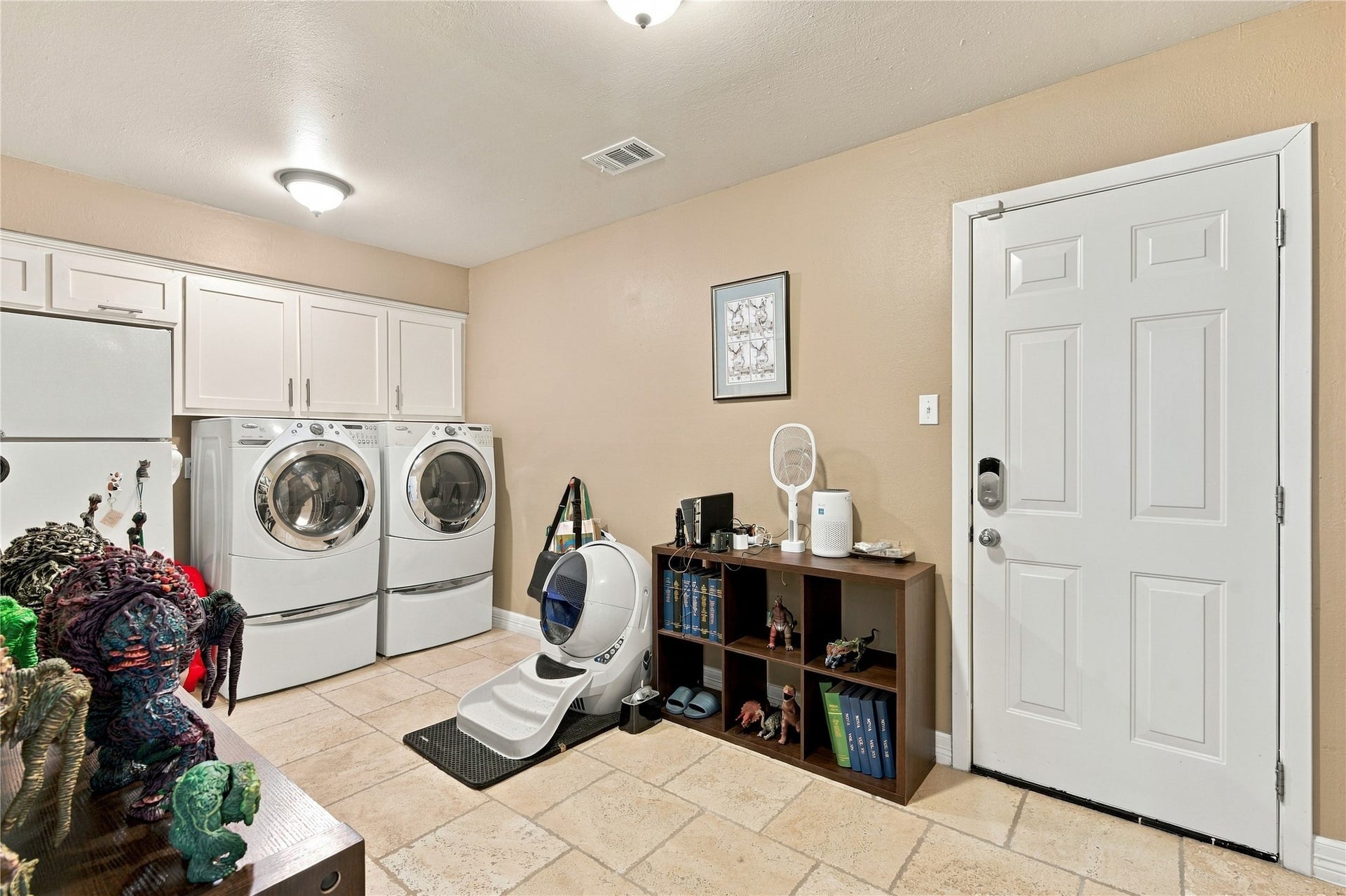 3211 Chris Drive, Houston, TX 77063 This spacious utility room is just steps off of the kitchen and seamlessly connects to the garage making unloading groceries a breeze. The room also boasts additional storage space above the washer and dryer in addition to a dedicated space for an additional refrigerator.
