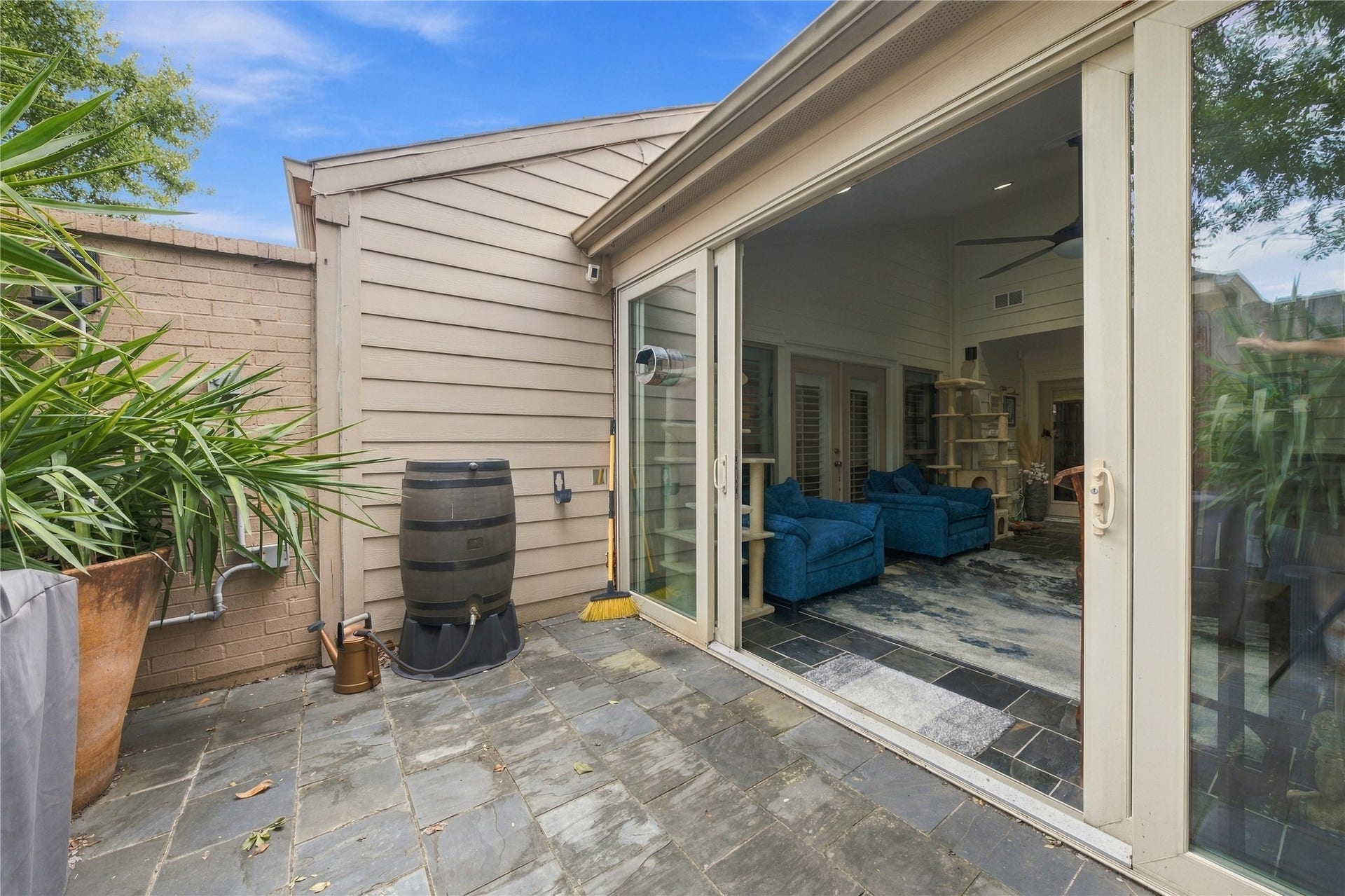 3211 Chris Drive, Houston, TX 77063 From outside, the sunroom's glass wall slides fully open onto slate pavers, while the privacy fence keeps this patio secluded.