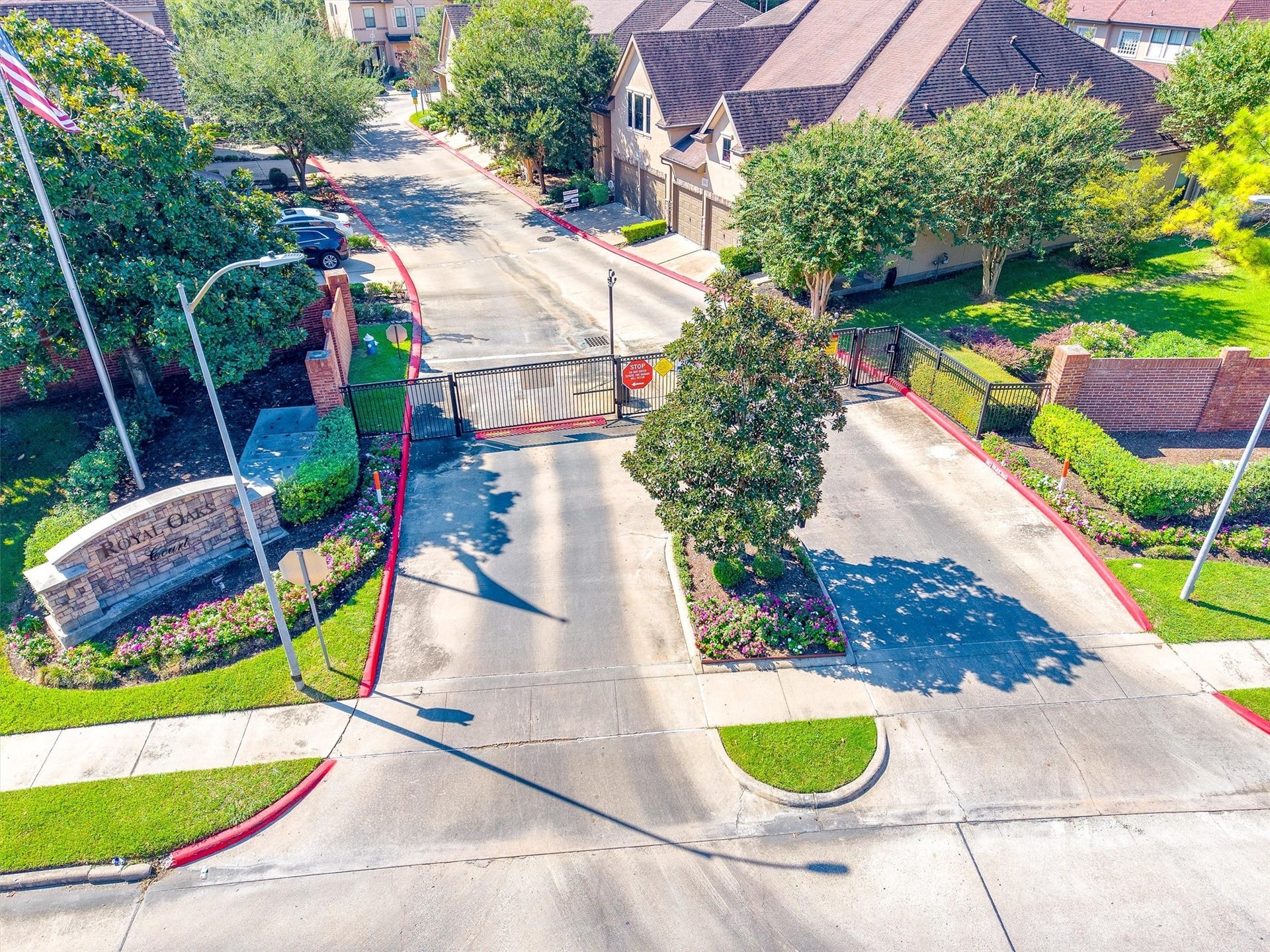 2919 Royal Oaks Crest, Houston, TX 77082 Gated community entrance with lush landscaping and a welcoming stone sign, offering privacy and security.