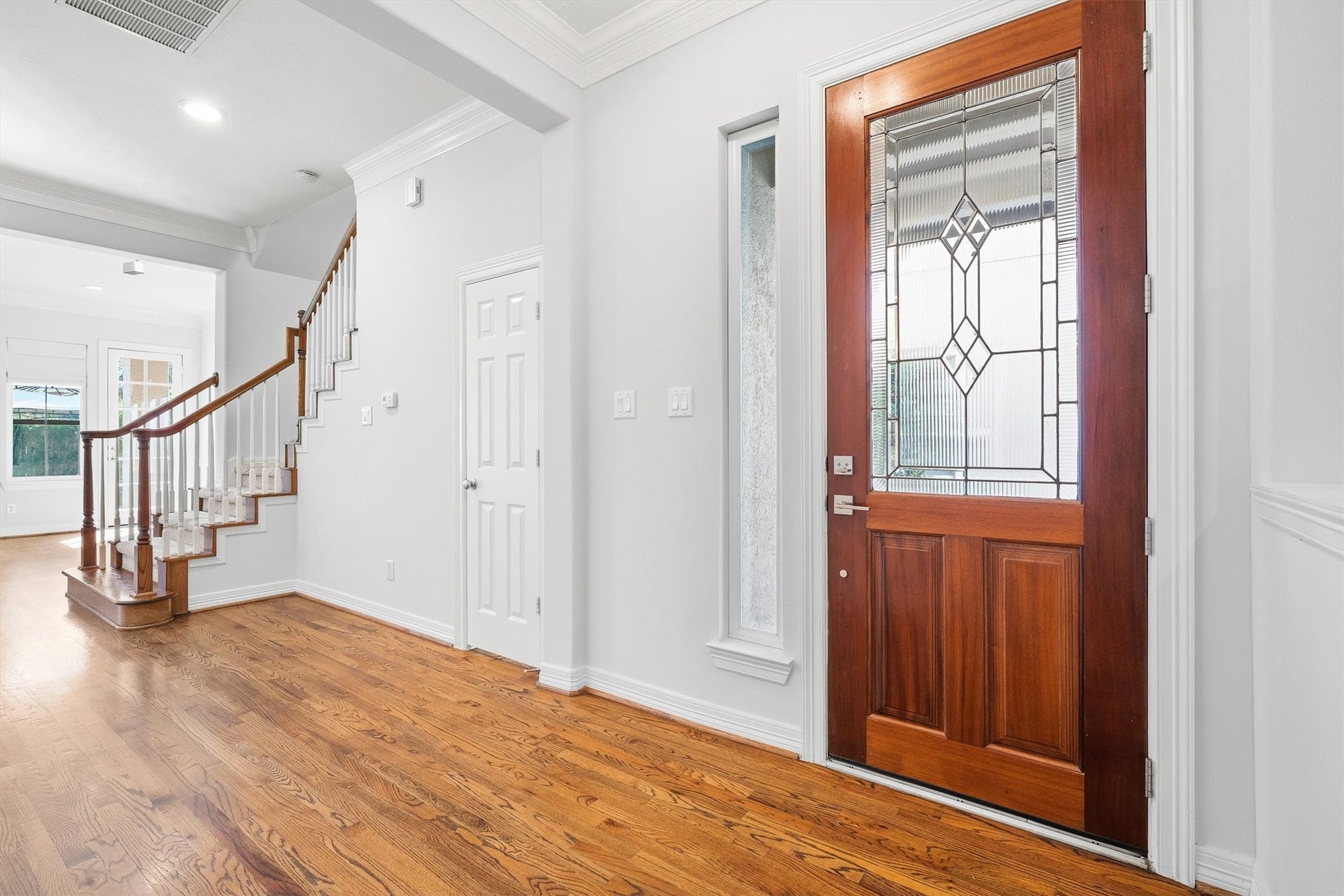 2919 Royal Oaks Crest, Houston, TX 77082 Inviting foyer featuring a beautiful wooden front door with decorative glass, leading to a bright interior with elegant hardwood flooring and a graceful staircase.
