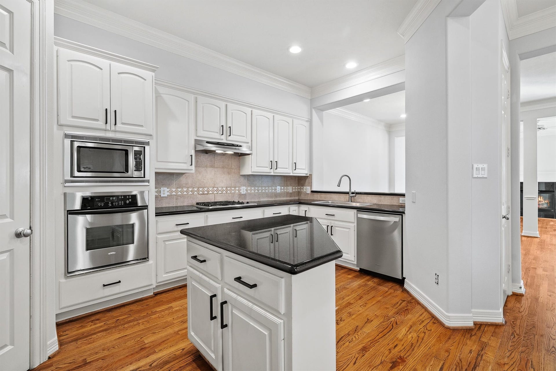 2919 Royal Oaks Crest, Houston, TX 77082 Spacious kitchen with sleek black countertops, white cabinetry, and stainless steel appliances, complemented by warm hardwood floors.