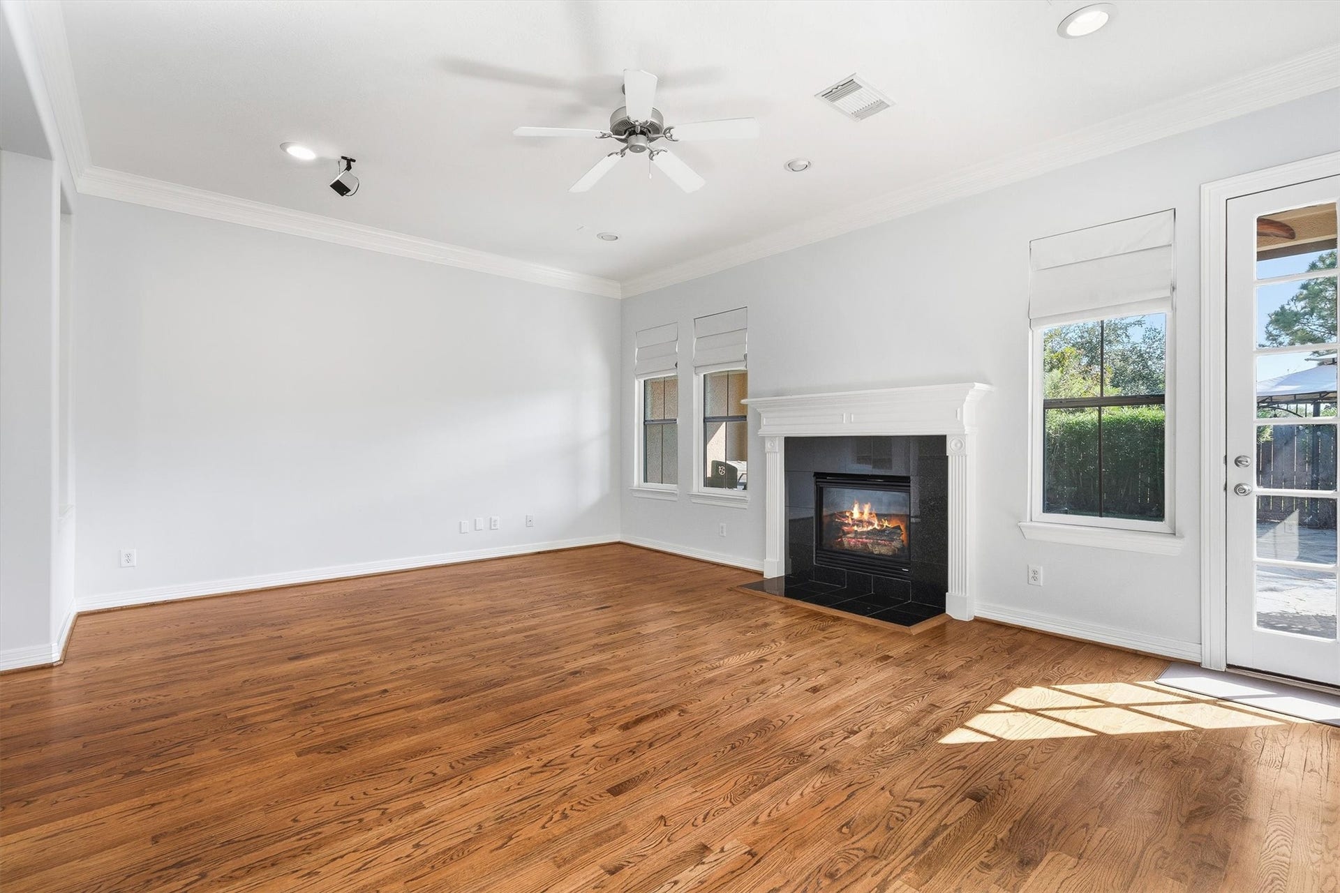 2919 Royal Oaks Crest, Houston, TX 77082 Spacious living room featuring elegant hardwood floors, a cozy fireplace, and abundant natural light through large windows and a glass door.