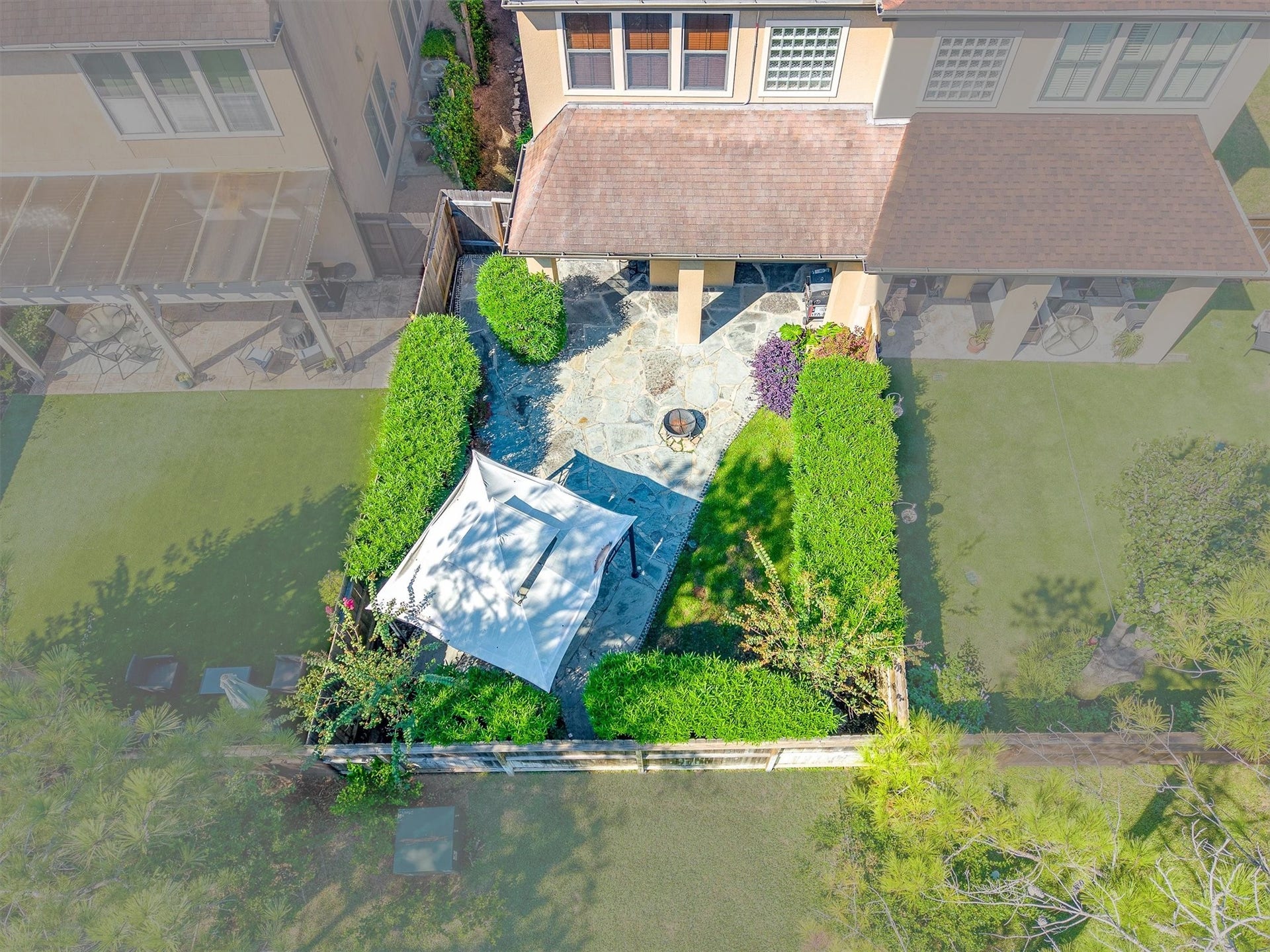 2919 Royal Oaks Crest, Houston, TX 77082 Charming backyard retreat featuring a stone patio, lush greenery, a cozy fire pit, and a shaded canopy area perfect for outdoor relaxation and entertaining.