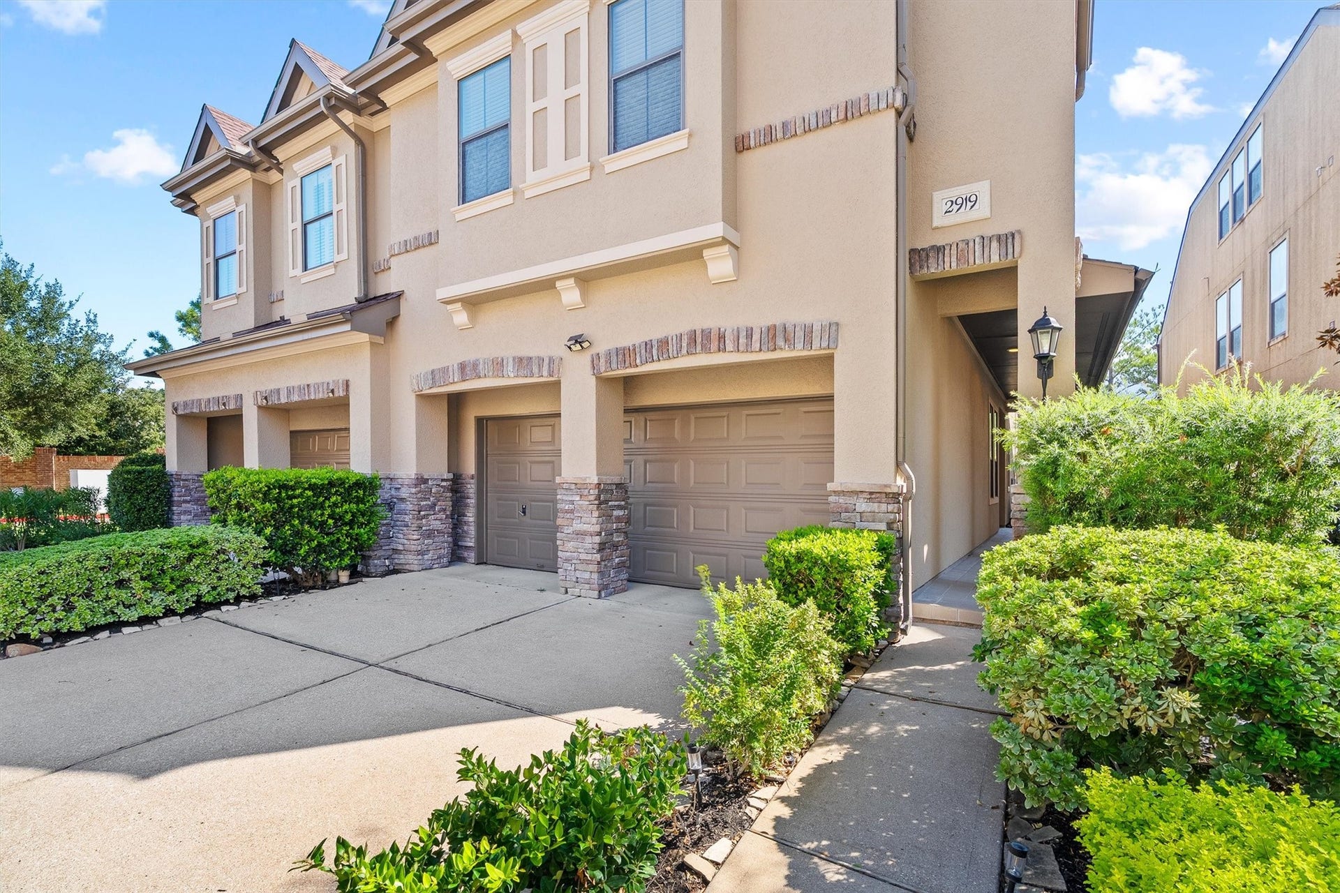 2919 Royal Oaks Crest, Houston, TX 77082 Great townhouse with a two-car garage, elegant brick accents, and well-manicured landscaping leading to a welcoming front entrance.