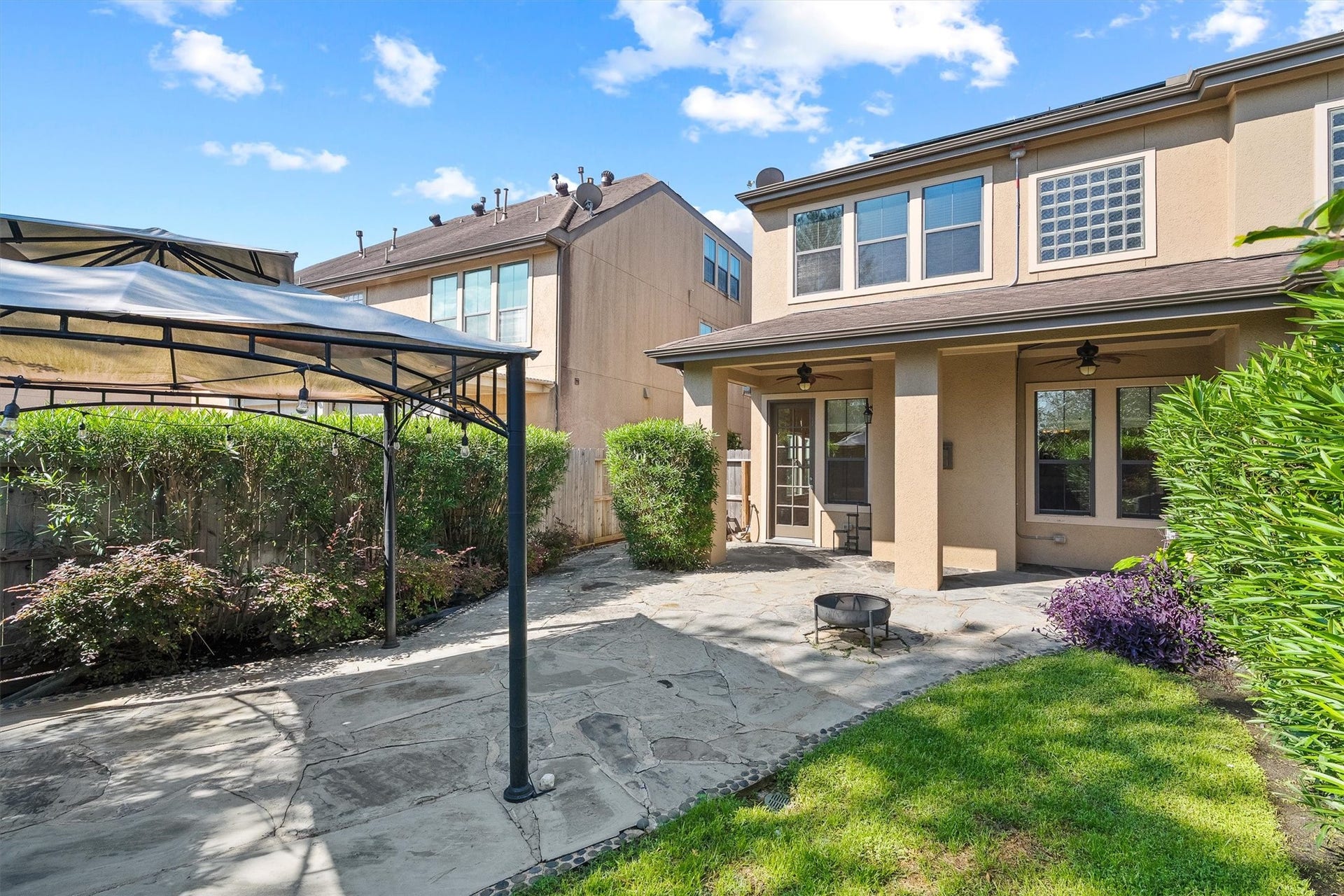 2919 Royal Oaks Crest, Houston, TX 77082 A backyard featuring a spacious patio with a pergola, lush greenery, and a cozy fire pit, perfect for outdoor entertaining.