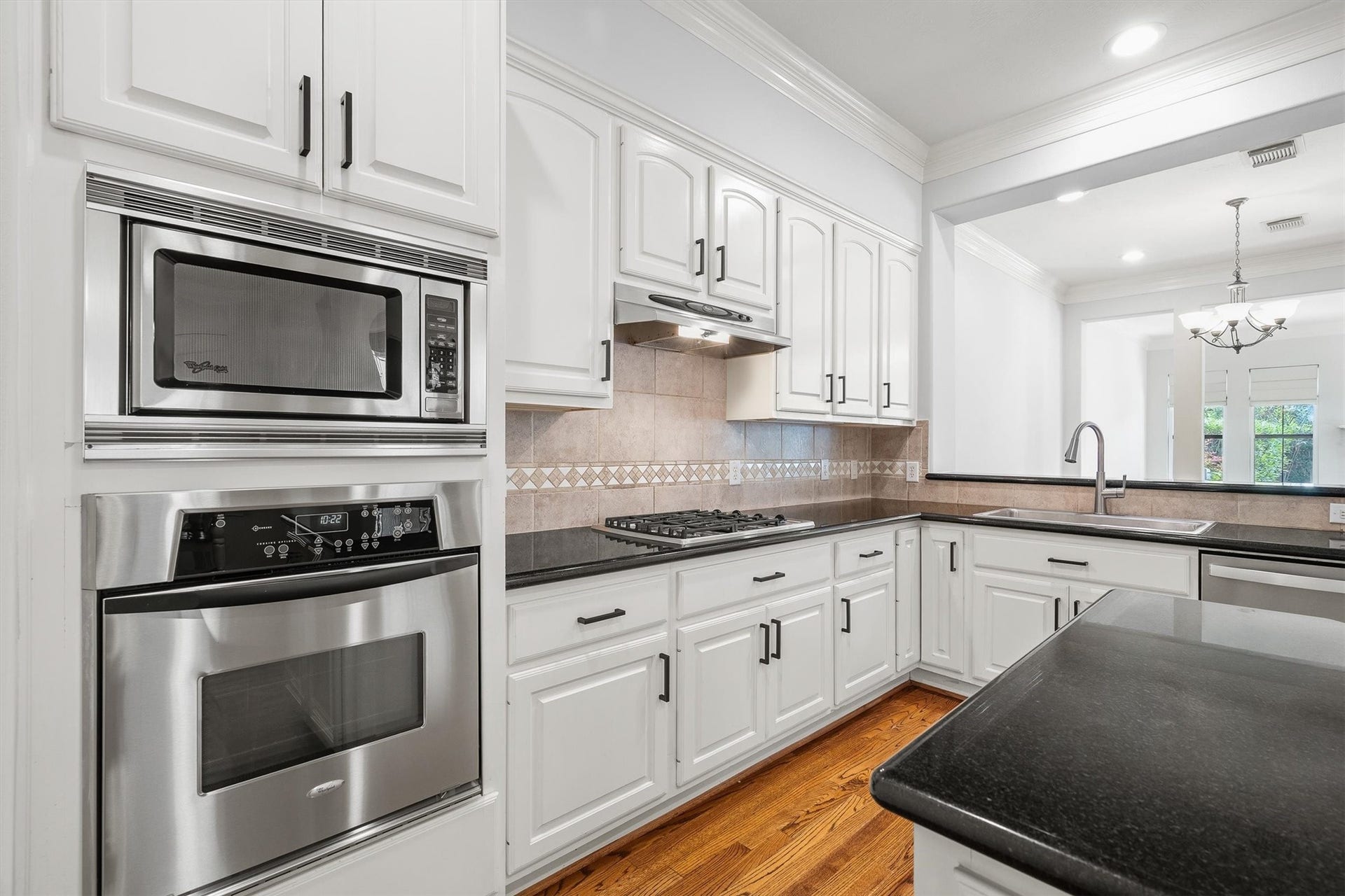 2919 Royal Oaks Crest, Houston, TX 77082 Modern kitchen with sleek stainless steel appliances, ample white cabinetry, and elegant black countertops, offering a bright and functional space for cooking and entertaining.