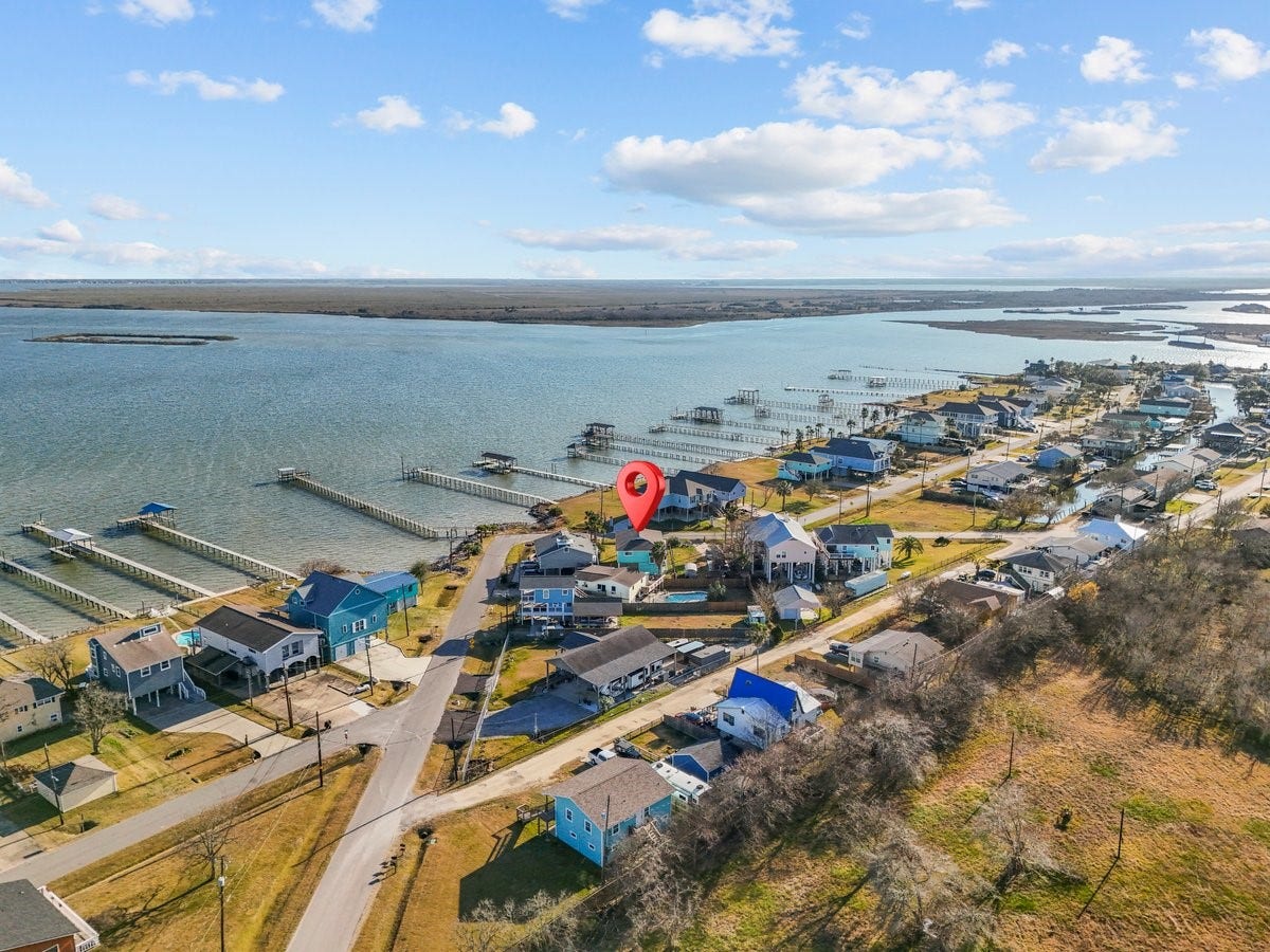 2406 Avenue P, San Leon, TX 77539 This photo showcases a charming coastal neighborhood with waterfront properties, docks, and scenic views of a bay. The area is marked by a pin, indicating a specific home, surrounded by well-maintained houses and lush greenery, perfect for those seeking a serene waterside lifestyle.