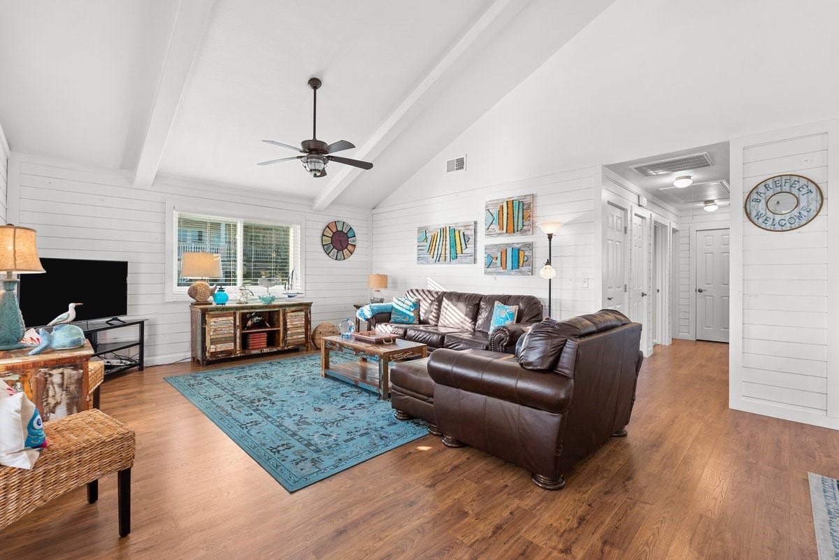 2406 Avenue P, San Leon, TX 77539 This inviting living room features vaulted ceilings, a ceiling fan, and abundant natural light. It boasts a cozy seating area with white shiplap walls to enhance the airy, coastal vibe.