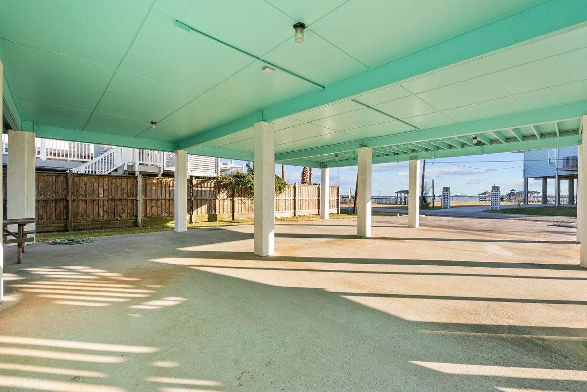 2406 Avenue P, San Leon, TX 77539 Spacious covered carport featuring sturdy support columns and a fenced backyard. Offers easy access to nearby amenities.