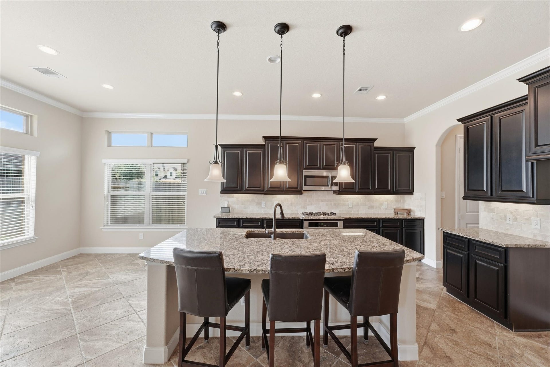 Island kitchen with breakfast bar, granite counters, and stainless steel appliances - all overlooking the living room with views to the backyard retreat.