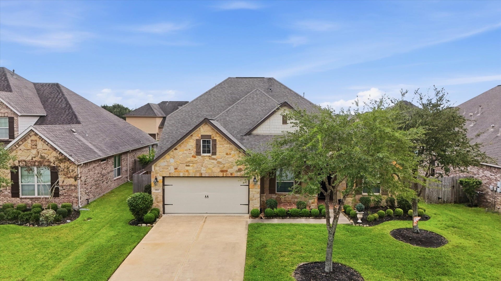 Brick and stone details, mature trees and a covered front porch create an inviting first impression.