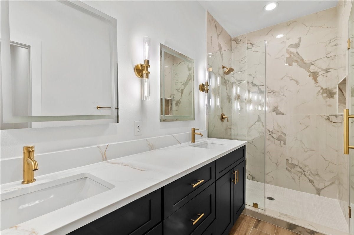 8323 Observatory Street, #A/B, Houston, TX 77088 Unit A - Luxurious primary suite bathroom featuring a spacious walk-in shower with elegant gold fixtures, dual vanities, and LED mirrors, creating a sophisticated spa-like retreat.