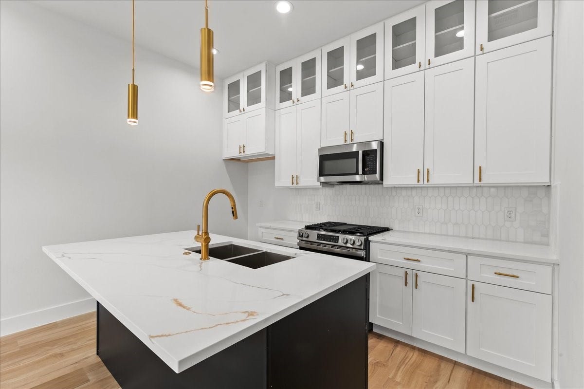 8323 Observatory Street, #A/B, Houston, TX 77088 Unit A - Enjoy a sleek, modern kitchen featuring a flat-top stove, stainless steel appliances, elegant gold fixtures, and designer finishes throughout.