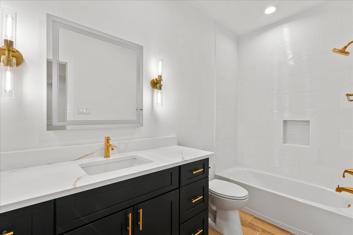 8323 Observatory Street, #A/B, Houston, TX 77088 Unit A - Secondary bathroom features a tub/shower combination accented with elegant gold fixtures and a modern LED vanity mirror, creating a stylish and functional space for family and guests.