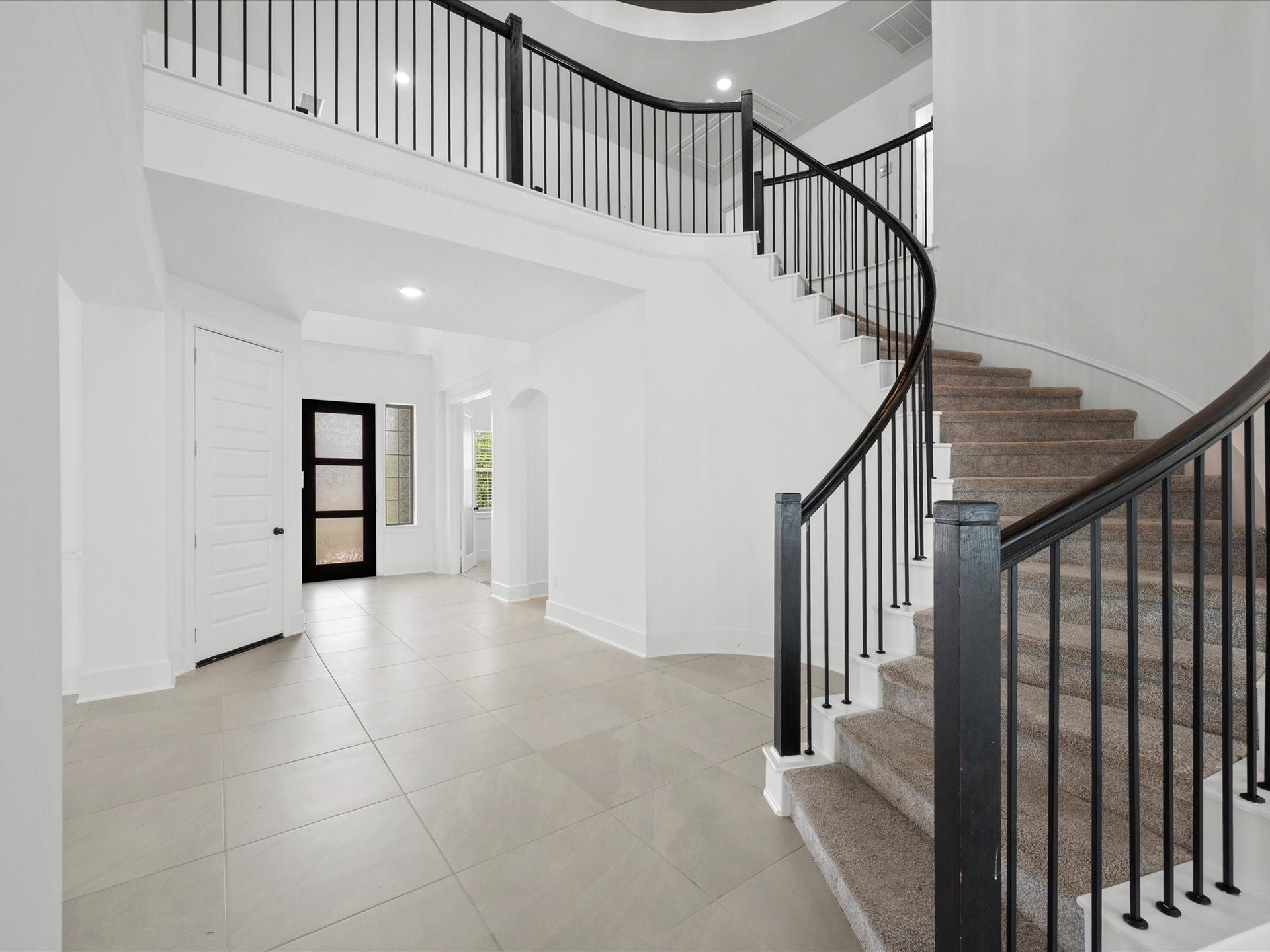 1911 Golden Leaf Drive, Missouri City, TX 77459 Dramatic rotunda entry with a rolling staircase, wrought iron railing, and soaring vaulted ceilings finished in striking black accents.