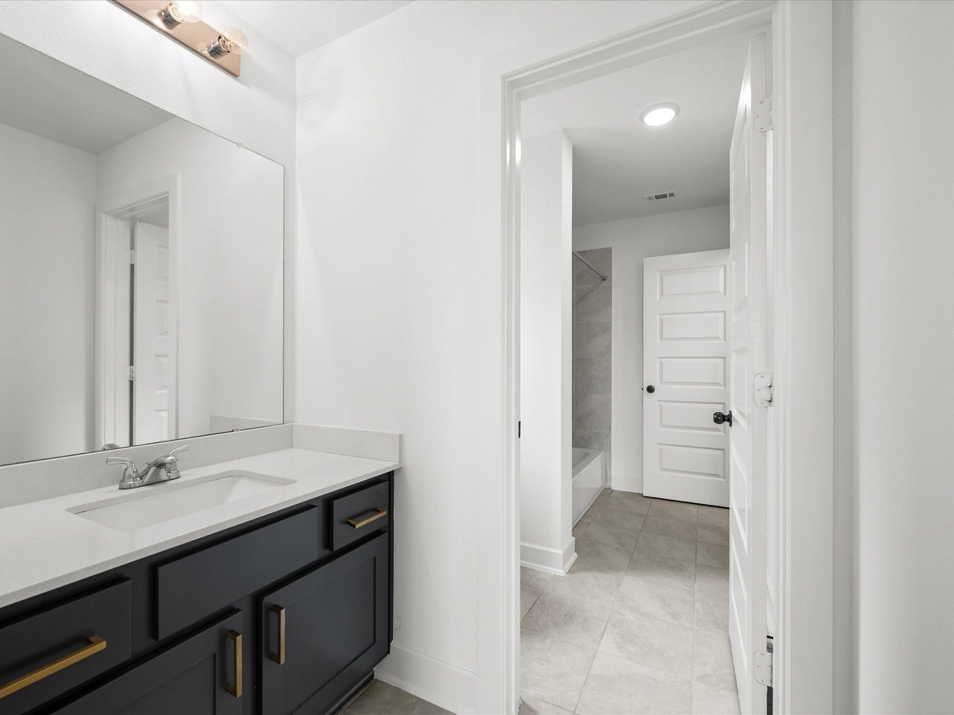 1911 Golden Leaf Drive, Missouri City, TX 77459 Upstairs bathroom hallway with dark cabinetry and gold fixtures.