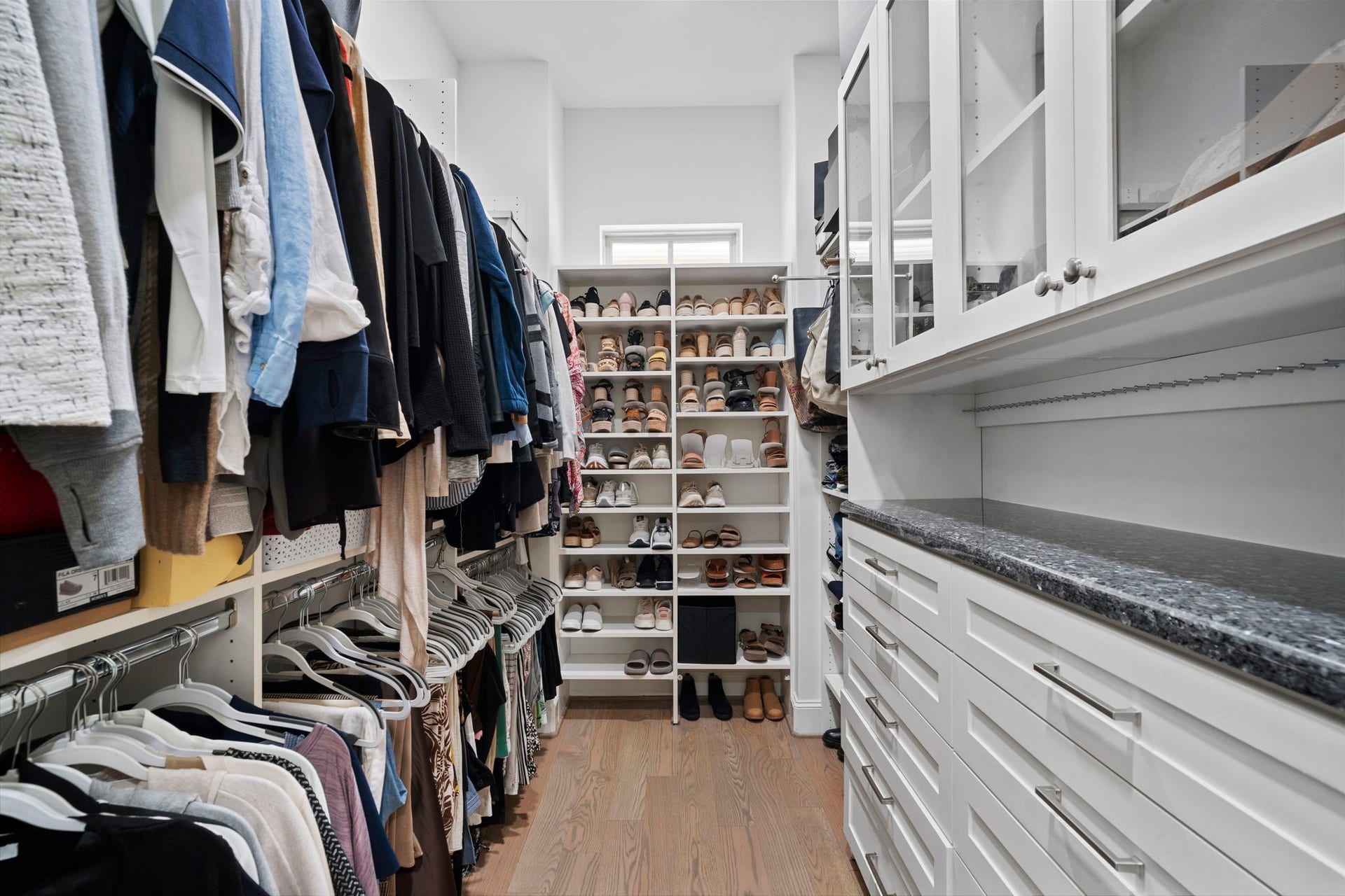 Walk-in primary closet with built-in shelving.