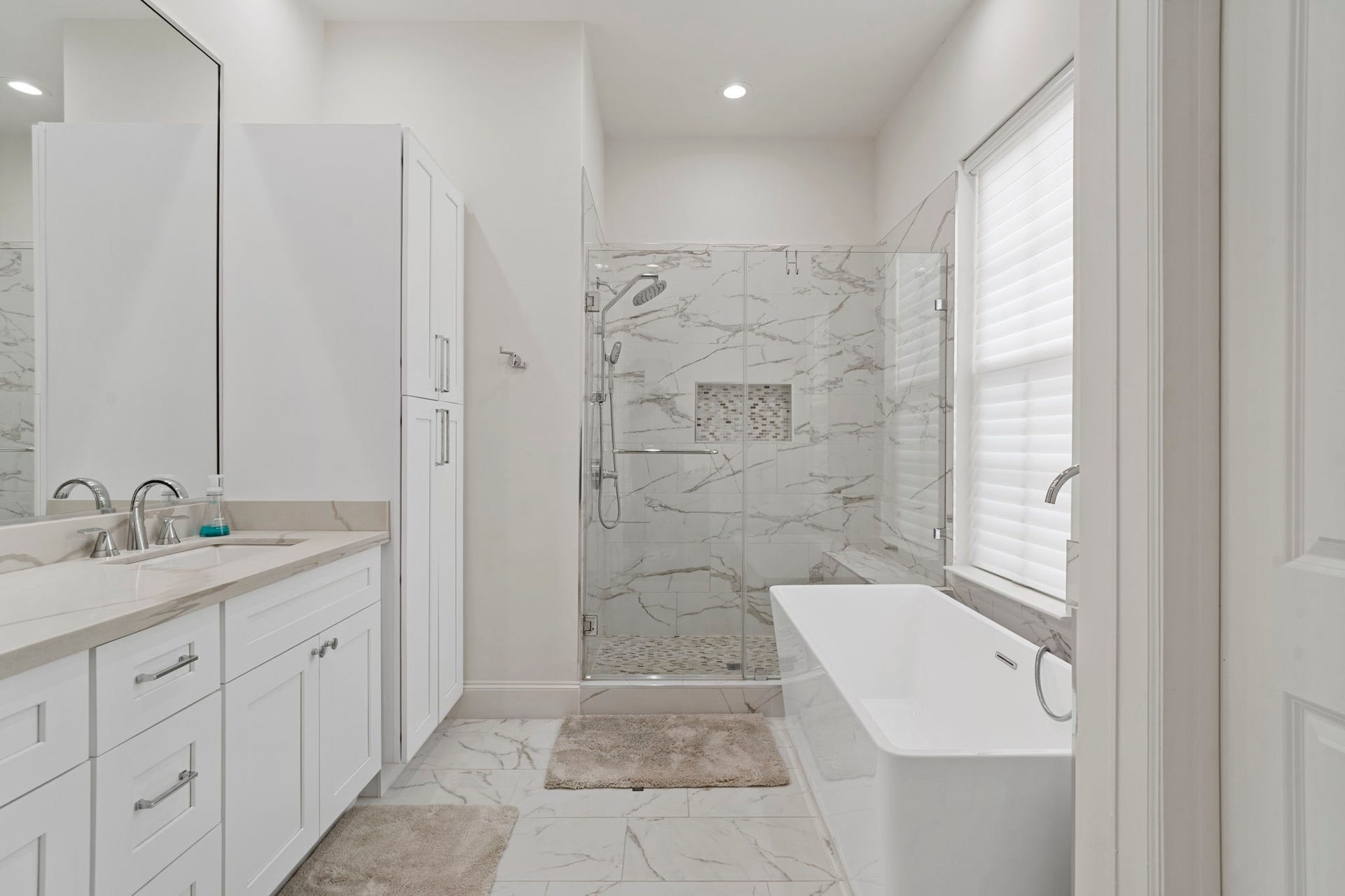 Primary bathroom with dual vanities, walk in shower, and soaking tub.