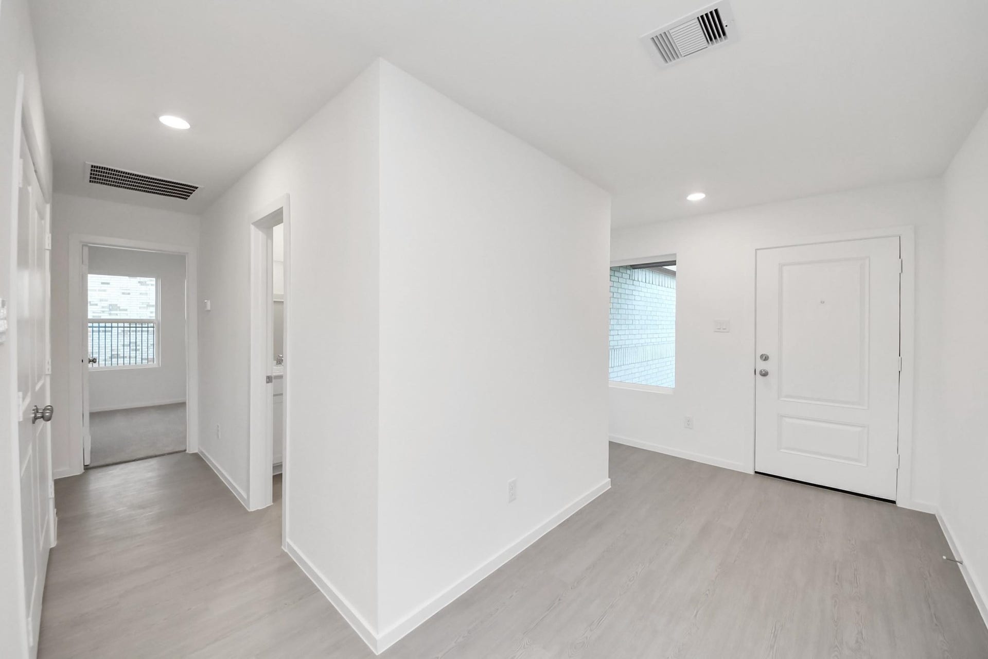 3096 Sunset Glory Drive, Katy, TX 77493 Bright and modern entryway with light wood flooring, white walls, and recessed lighting. It features a small hallway leading to other rooms, with a window and a door providing natural light.