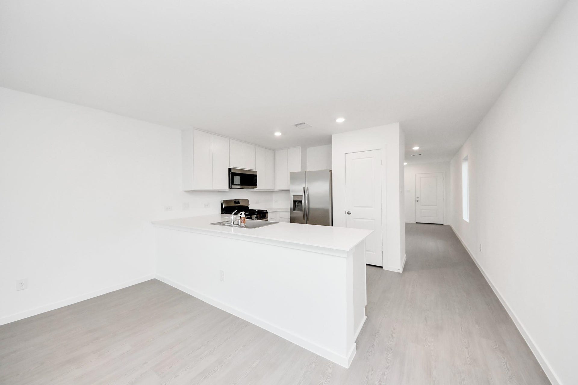 3096 Sunset Glory Drive, Katy, TX 77493 This photo showcases a modern, open-concept kitchen with sleek white cabinetry, stainless steel appliances, and light wood flooring. The space is bright and airy, enhancing its spacious feel.