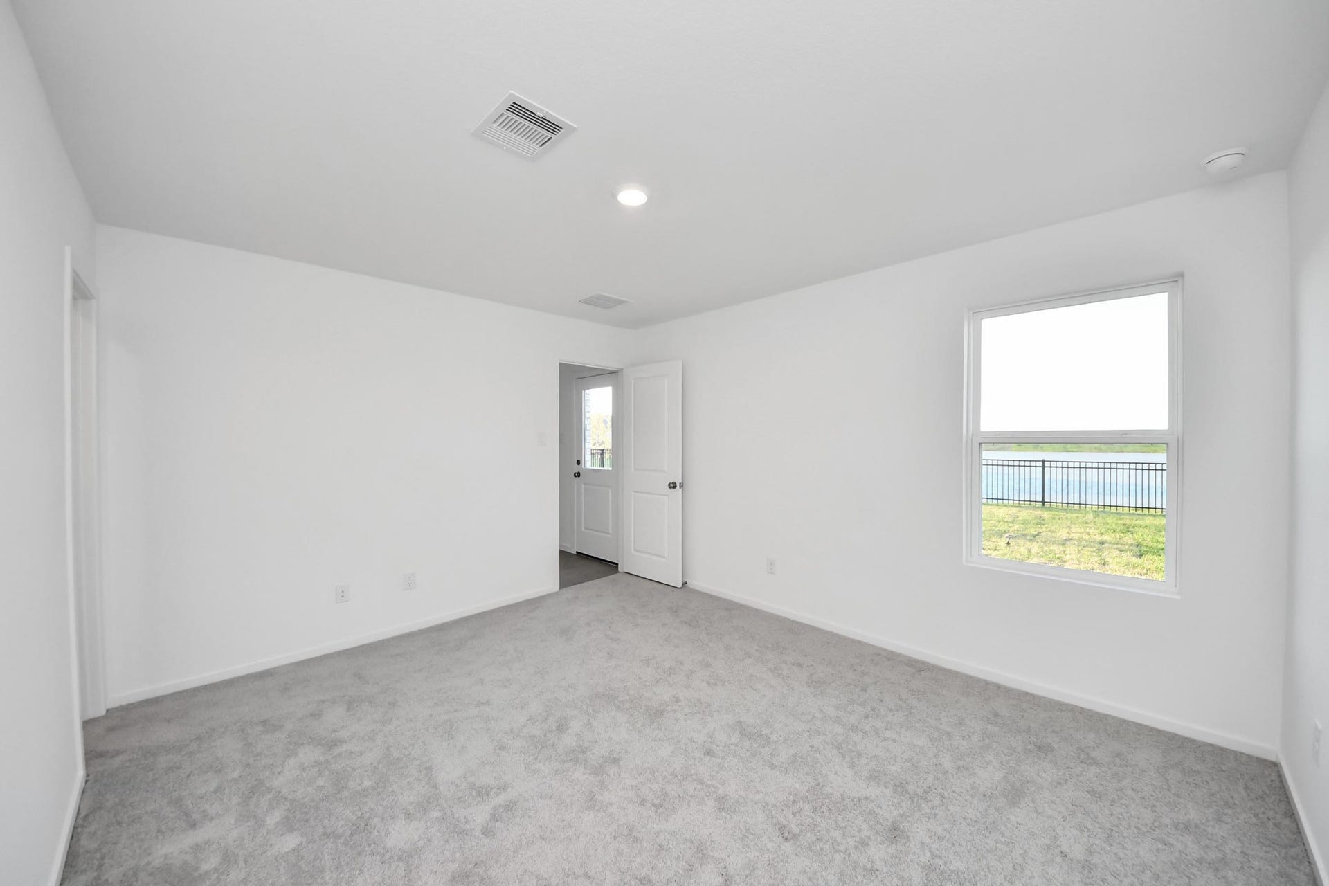 3096 Sunset Glory Drive, Katy, TX 77493 Experience serene comfort in this bright primary bedroom, featuring plush carpet, fresh white walls, and a window framing tranquil water views.