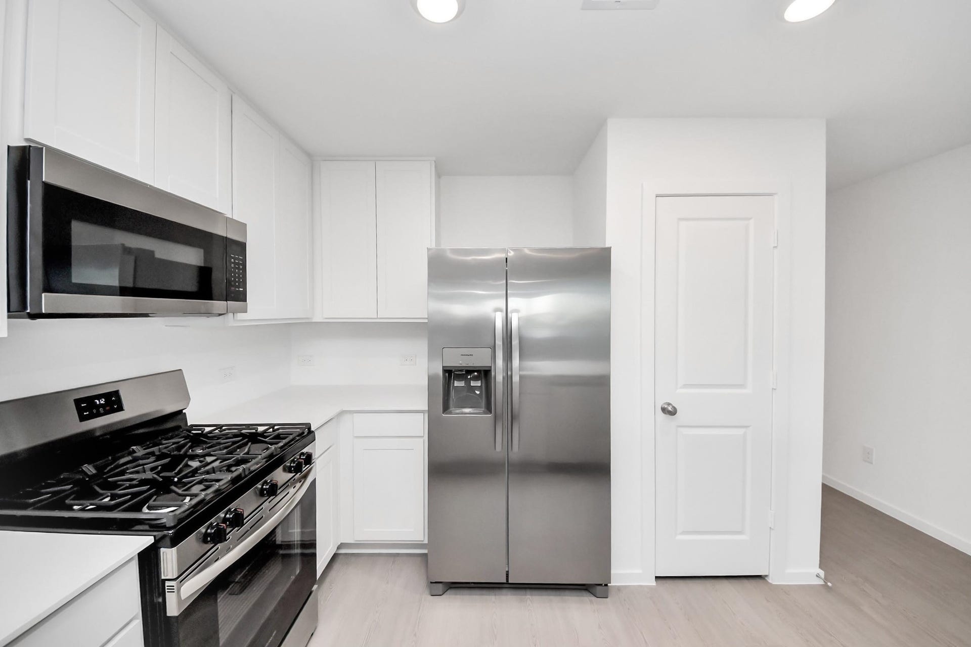 3096 Sunset Glory Drive, Katy, TX 77493 Modern kitchen with white cabinetry, stainless steel appliances including a gas stove and double-door refrigerator, and a sleek microwave. Bright and clean design with ample storage.