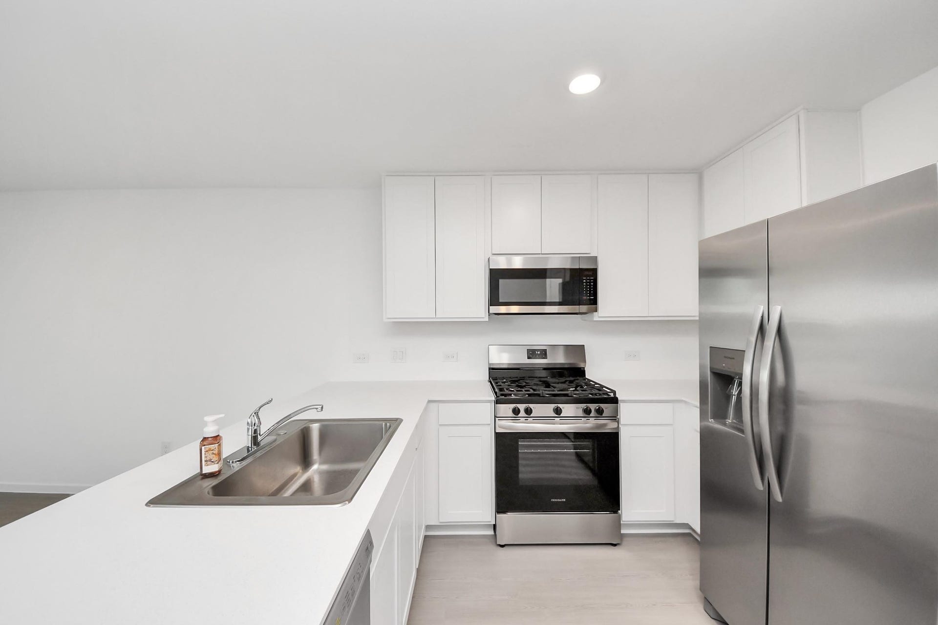 3096 Sunset Glory Drive, Katy, TX 77493 Modern kitchen with sleek stainless steel appliances, white cabinetry, and a spacious quartz countertop with a built-in farmhouse sink.