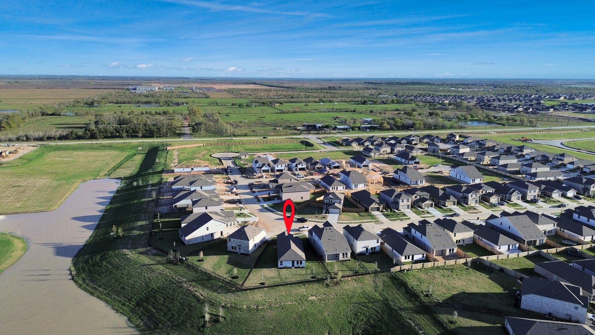 3096 Sunset Glory Drive, Katy, TX 77493 This aerial photo showcases a suburban neighborhood with modern homes, green spaces, and a scenic water feature. The highlighted property is centrally located, offering a spacious backyard and a peaceful setting with expansive views of the surrounding countryside.