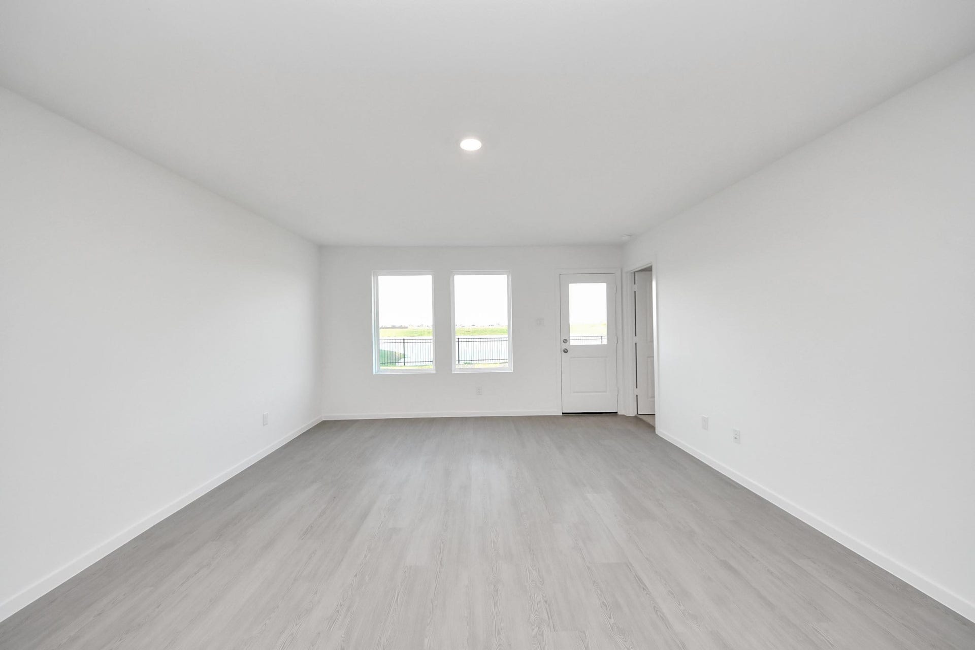 3096 Sunset Glory Drive, Katy, TX 77493 Bright and spacious room with light wood flooring and white walls. Features two large windows and a door, allowing plenty of natural light and offering outdoor access. Ideal for a living area or open-plan layout. Has great views of lake and backyard.