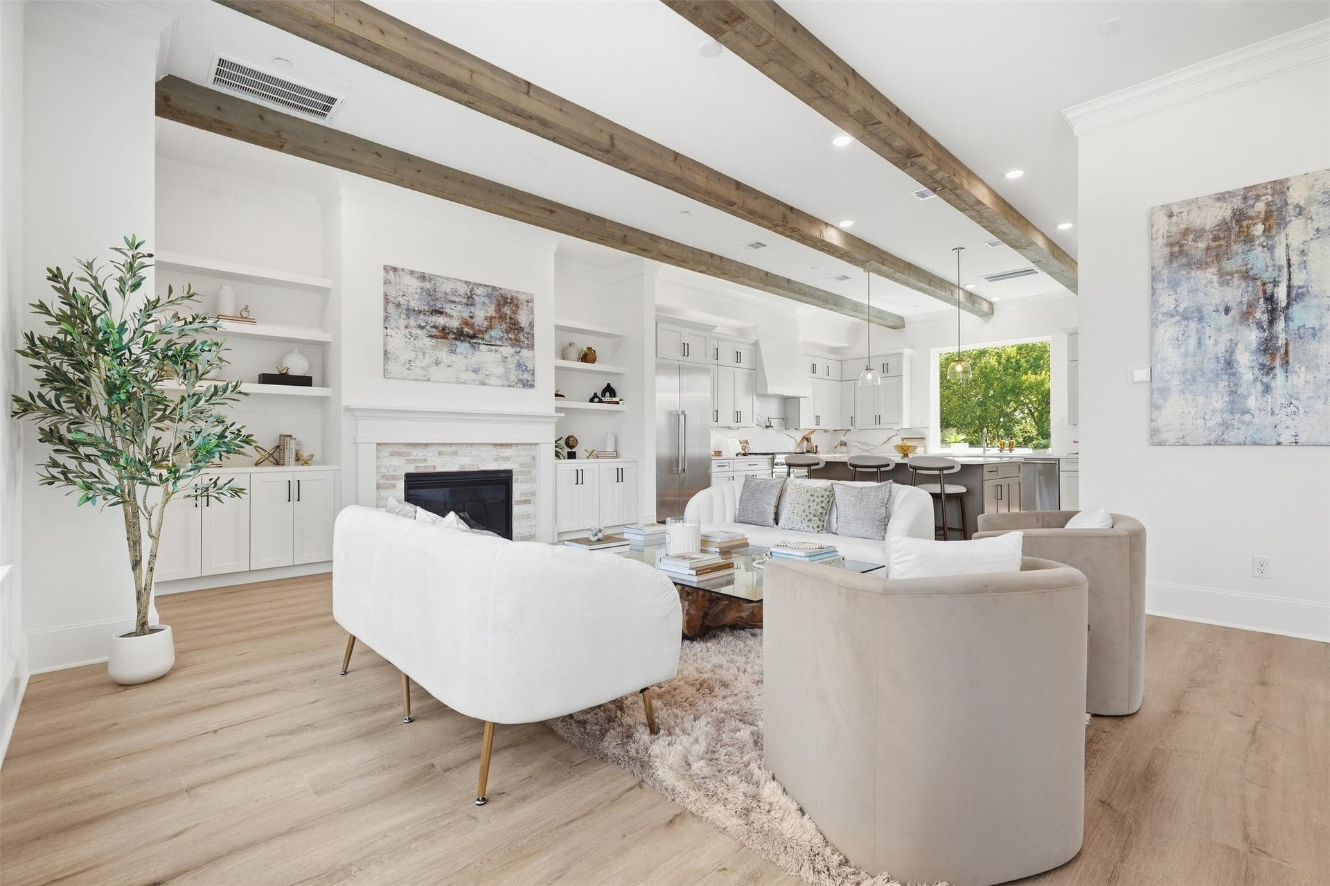 2111 Nantucket Drive, #C, Houston, TX 77057 Open-concept living and kitchen area featuring exposed wood beams, built-in cabinetry, a fireplace, and abundant natural light.