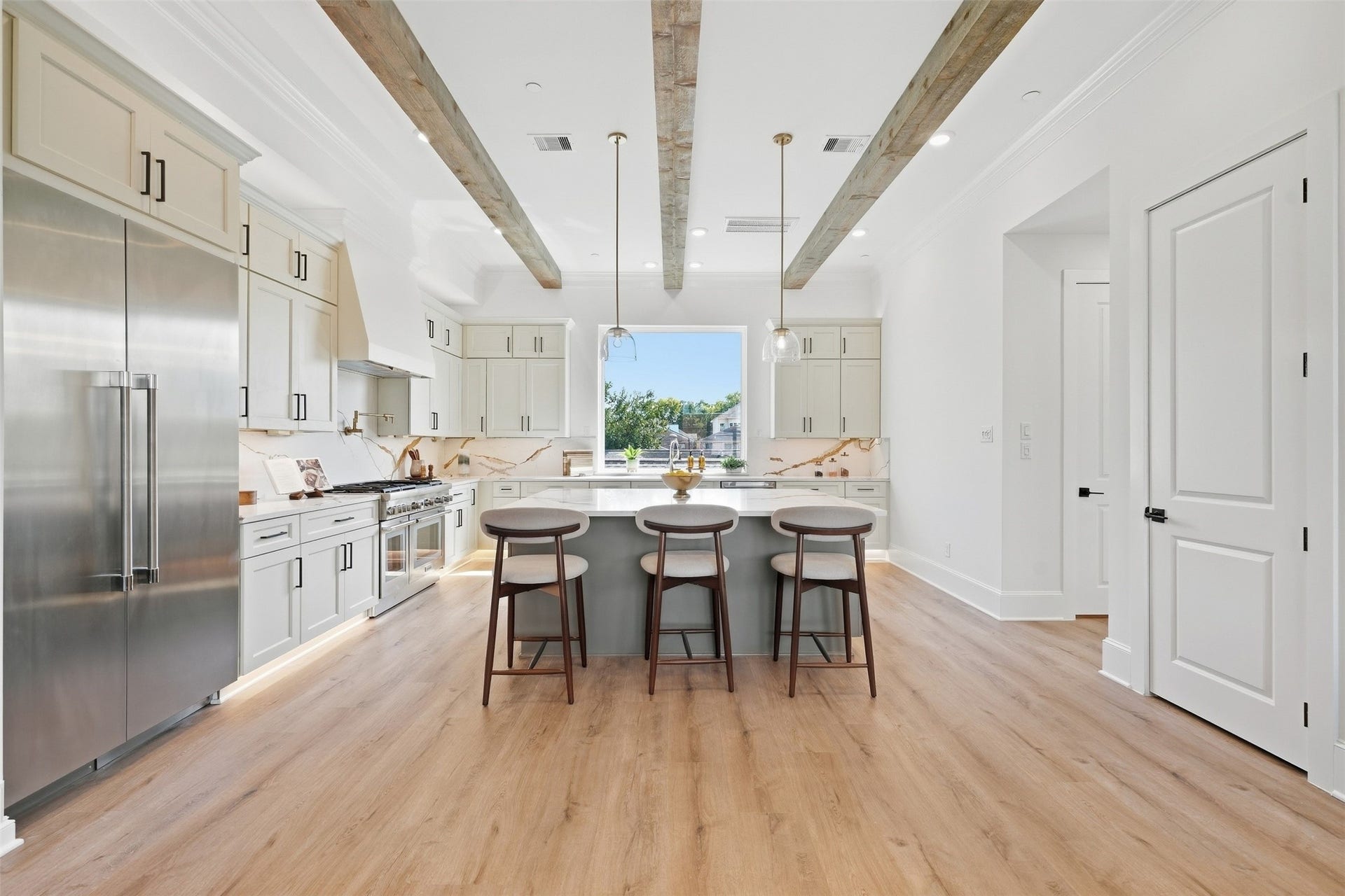 2111 Nantucket Drive, #C, Houston, TX 77057 Thoughtfully designed kitchen with an oversized island, extensive cabinetry, stainless steel appliances, statement backsplash, and exposed wood beams overhead.