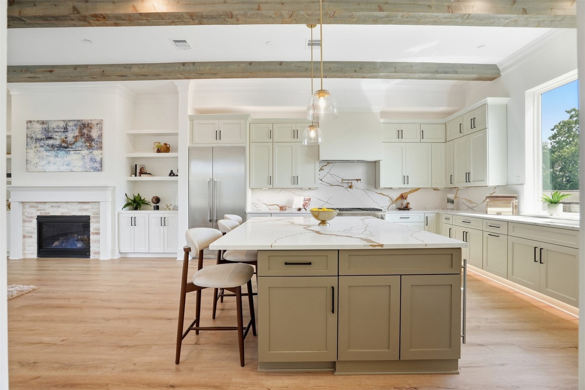2111 Nantucket Drive, #C, Houston, TX 77057 Expansive kitchen centered around an oversized island with generous seating, custom cabinetry, statement countertops and backsplash, and views into the adjoining living area and fireplace.