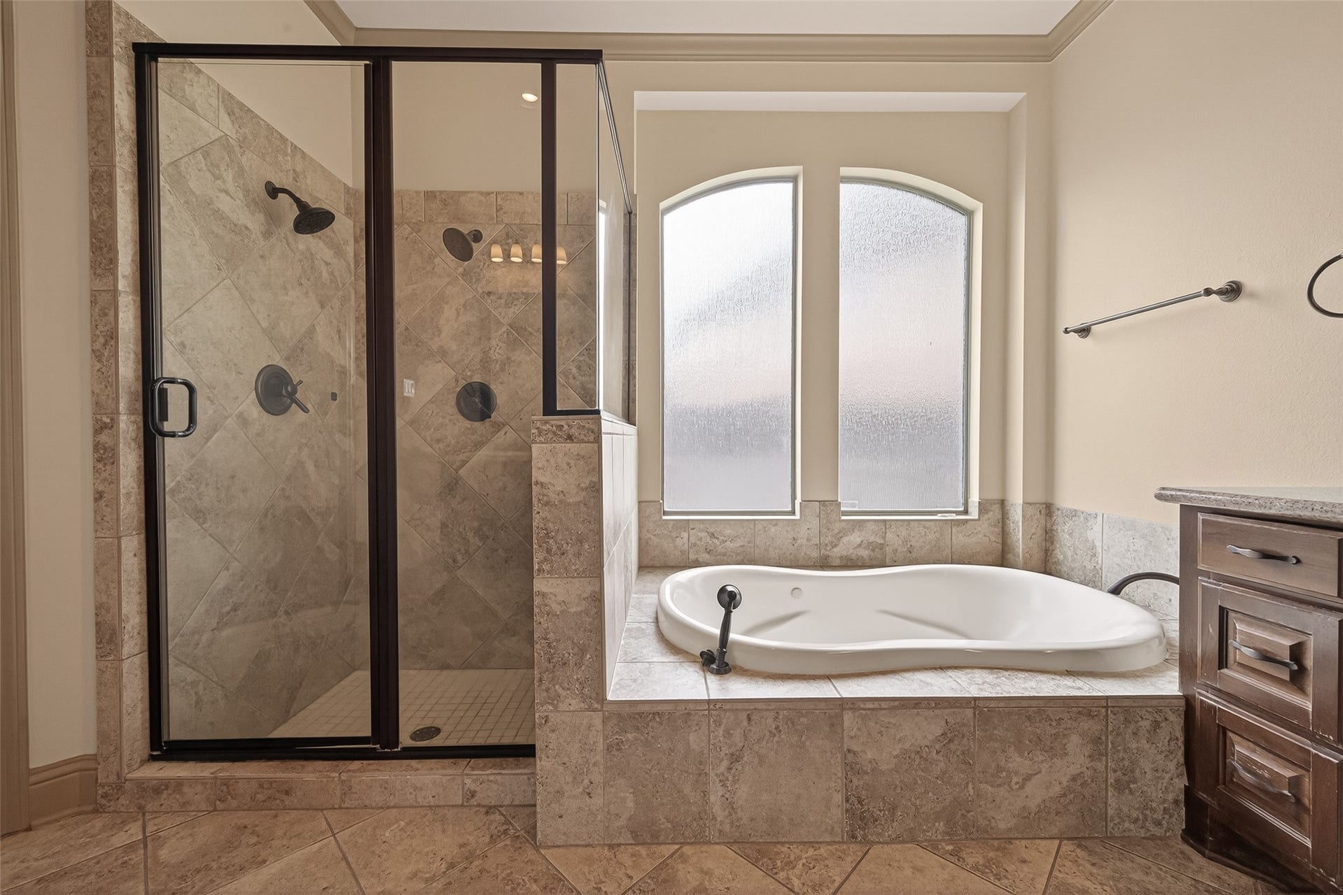 27411 Manor Falls Lane, Fulshear, TX 77441 The tile surrounded soaking tub is nestled beneath an elegant arched privacy window that fills the space with soft, natural light. Adjacent to the tub, the glass enclosed shower features diagonal tile work, oil rubbed bronze fixtures, and a built in niche for convenience. This spa like setup offers the best of both worlds for relaxation and daily use.
