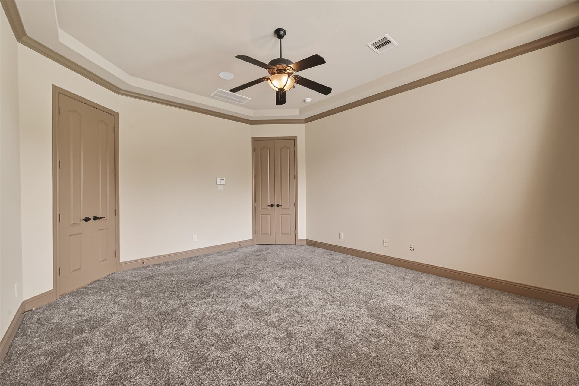 27411 Manor Falls Lane, Fulshear, TX 77441 This spacious primary bedroom offers a peaceful retreat with plush carpeting, a lovely tray ceiling with crown molding, and a ceiling fan for year-round comfort. The generous layout provides endless possibilities for furniture arrangements, while two doors offer access to the primary bathroom and closet, adding both privacy and convenience.