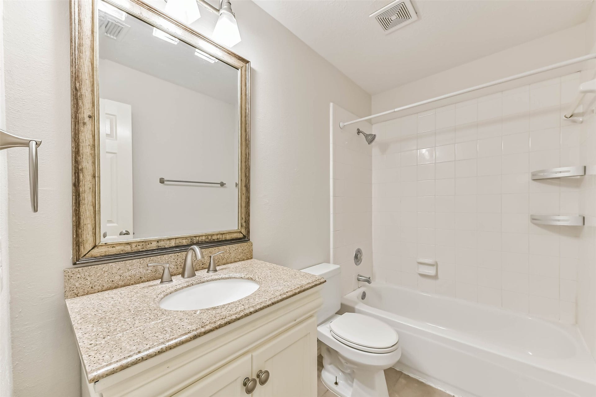 A full bath adds everyday convenience for the secondary rooms and visiting guests. The tub-and-shower combination offers bathing flexibility, while vanity storage keeps essentials handy and a framed mirror adds a polished touch.