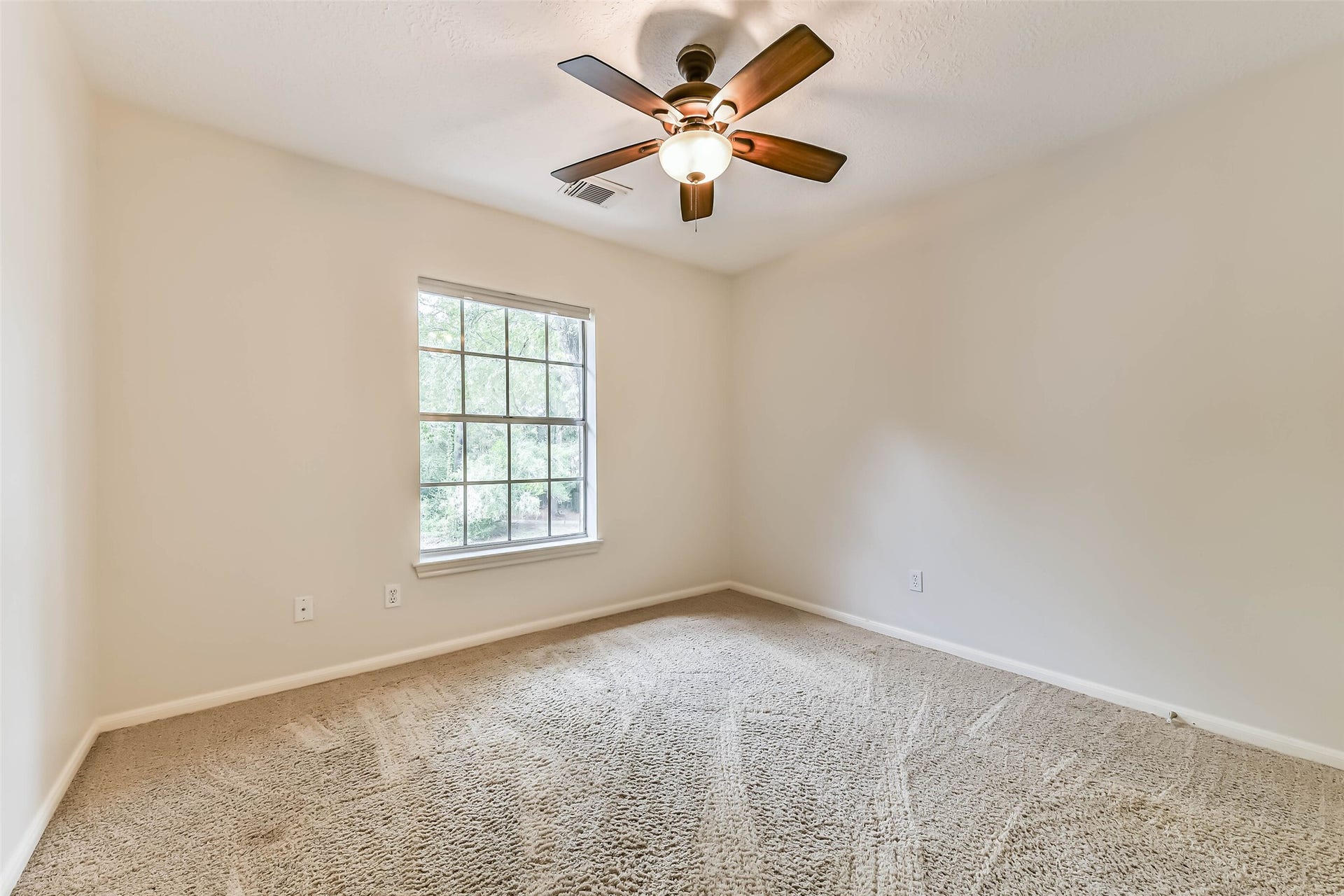 A leafy window view adds a pleasant backdrop to this inviting bedroom. Picture a cozy place to recharge, welcome overnight guests or settle in with a book, with neutral finishes ready for your personal touch.
