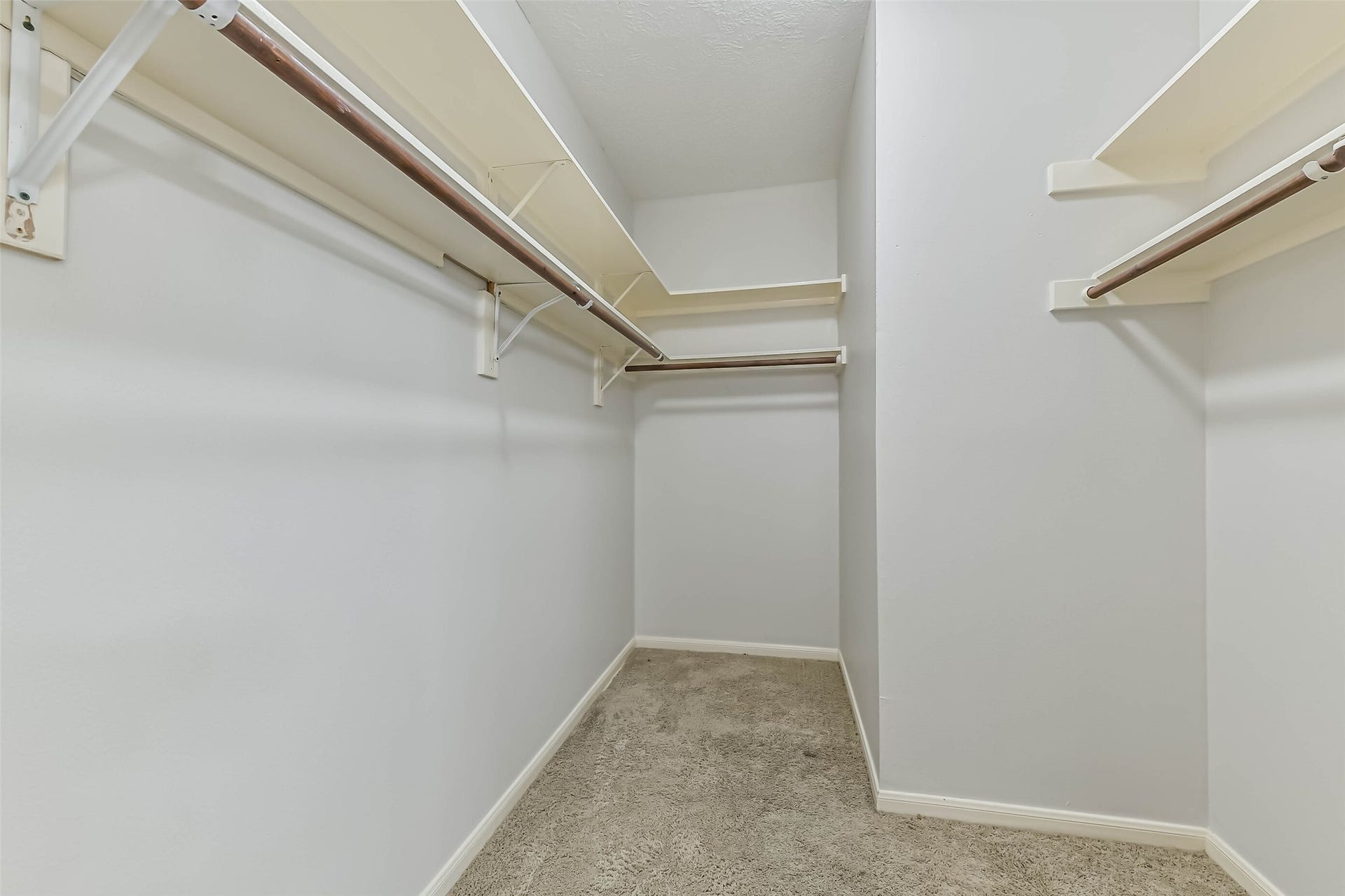 A place for your wardrobe, with hanging space along multiple walls and overhead shelves for accessories and seasonal essentials. This walk-in closet makes it easier to keep clothing organized and your bedroom focused on rest.