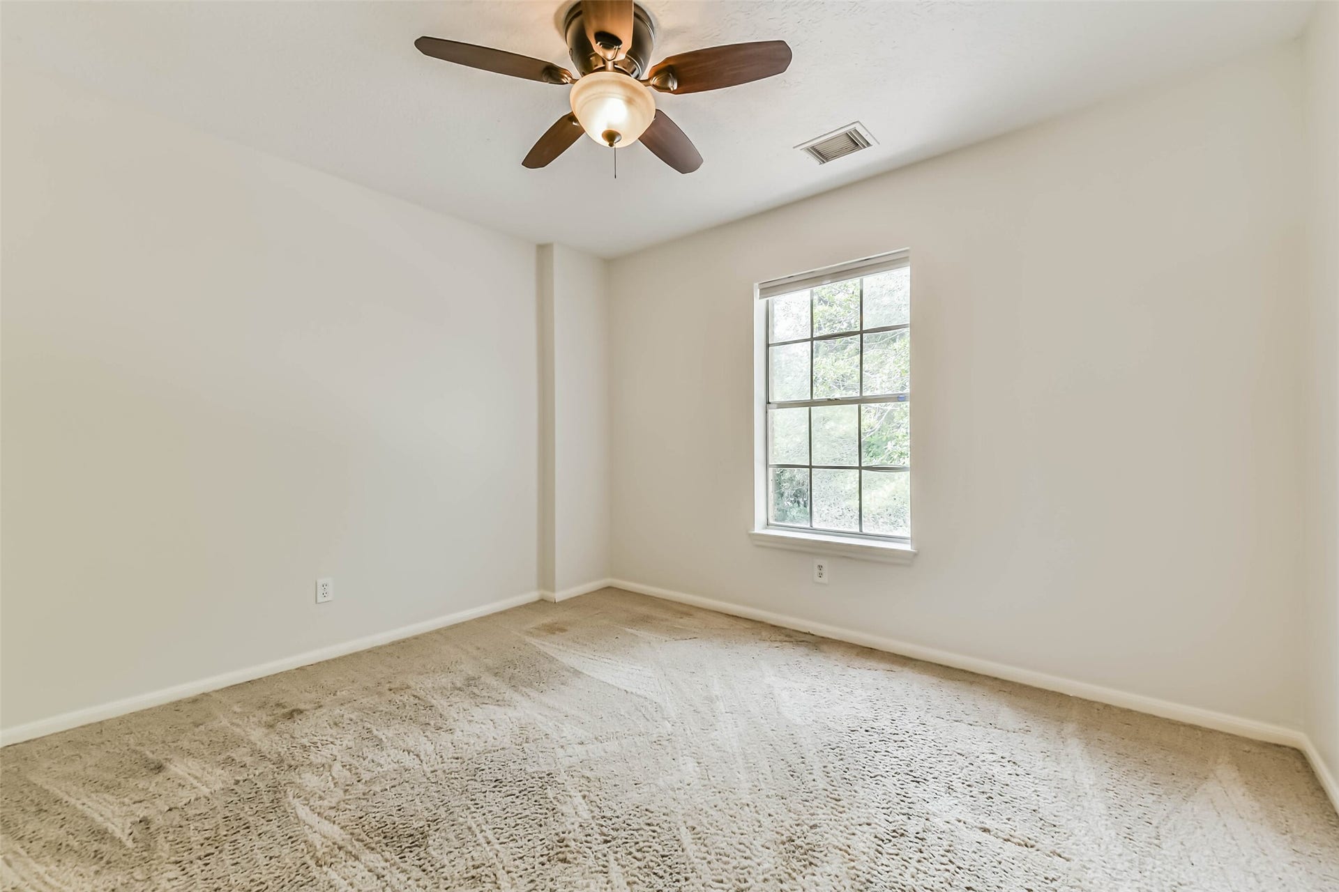 Make this light-filled room a welcoming place to rest or pursue your favorite projects. A window overlooking greenery and simple, neutral finishes offer an easy starting point for a guest room, personal retreat or creative workspace.