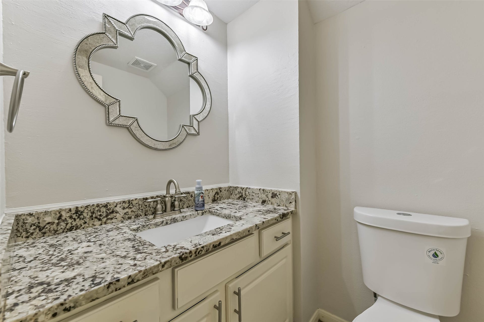 A welcoming finishing touch for visiting guests, this powder room pairs a decorative mirror with a spacious vanity. Cabinet and drawer storage keep essentials tucked away, leaving the countertop ready for a few thoughtful accents.
